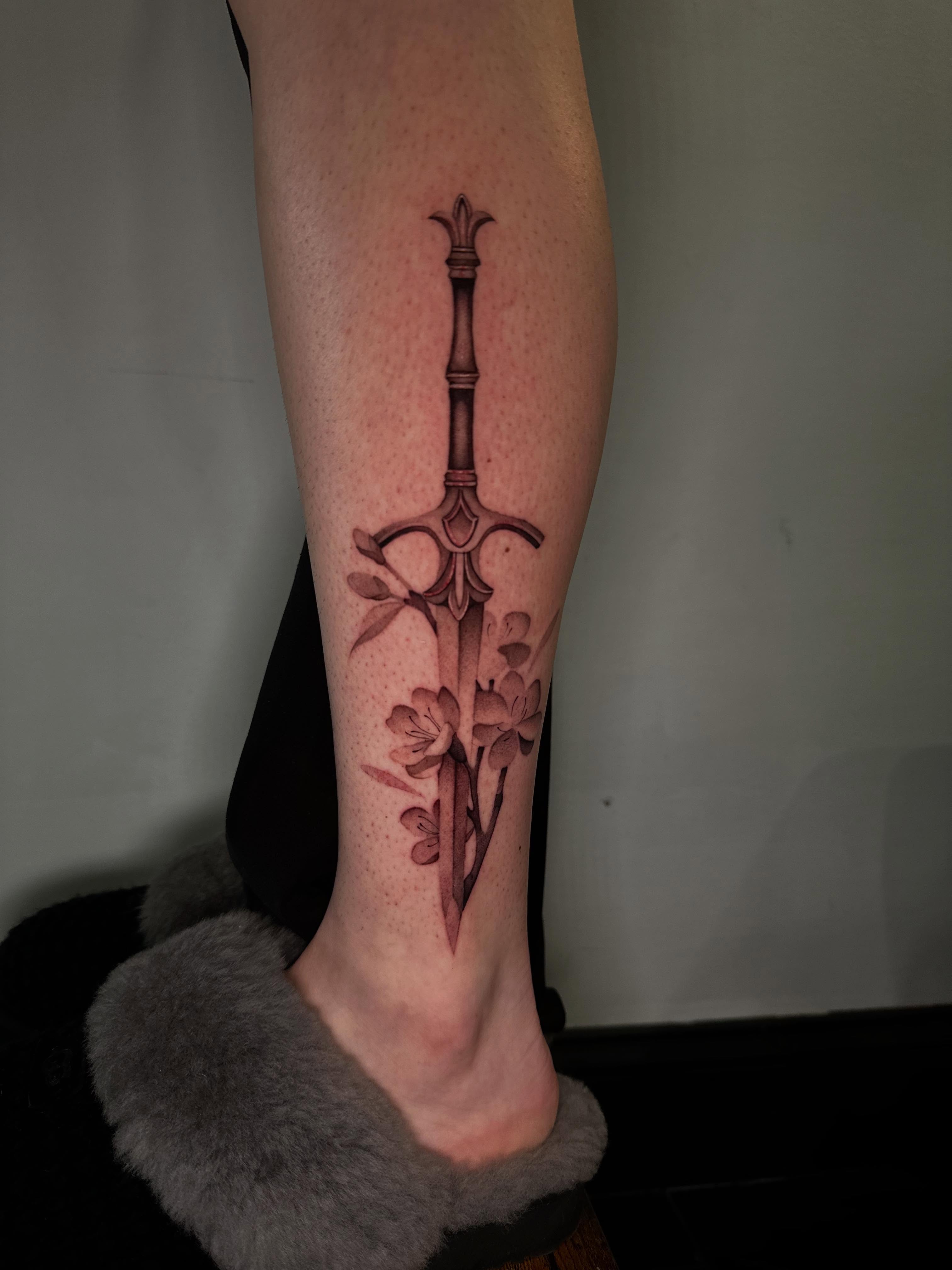 Sword and flowers black and grey tattoo on the calf by @piinkywabbiit, Roselle Park, New Jersey