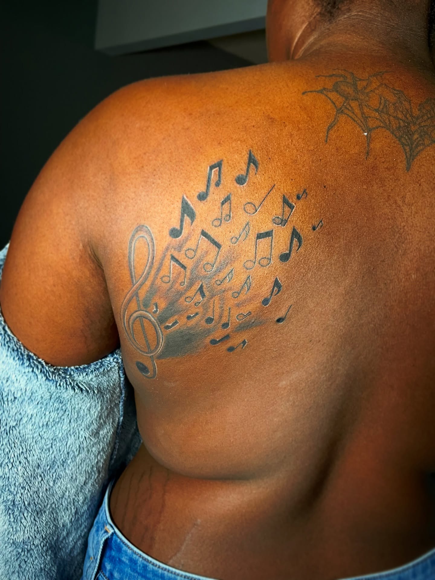 Music notes black and grey tattoo on the shoulder by The Reelist Ink