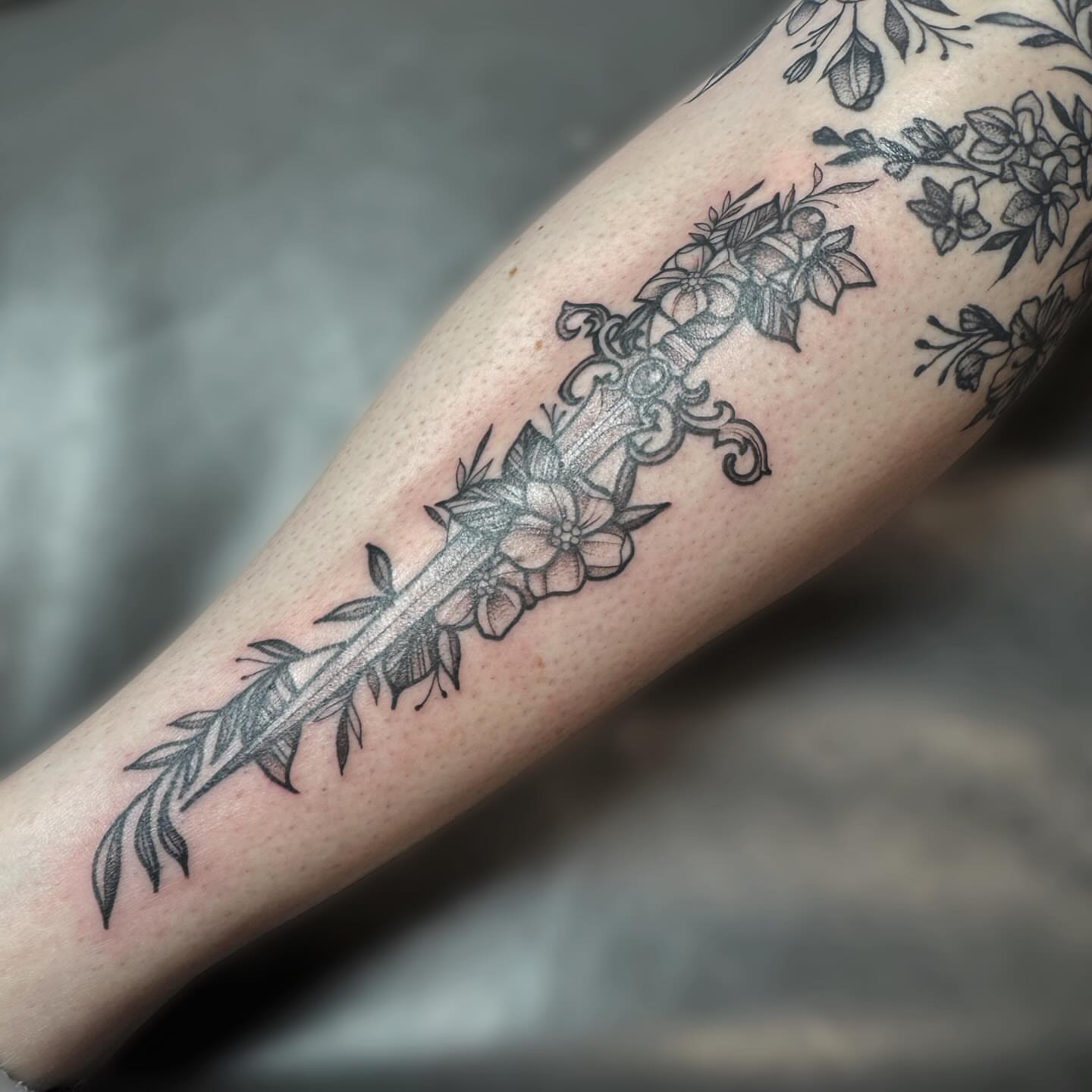 Sword and floral black and grey tattoo on the forearm by Kelsey 🖤 Tattoo Artist, Waterford Township