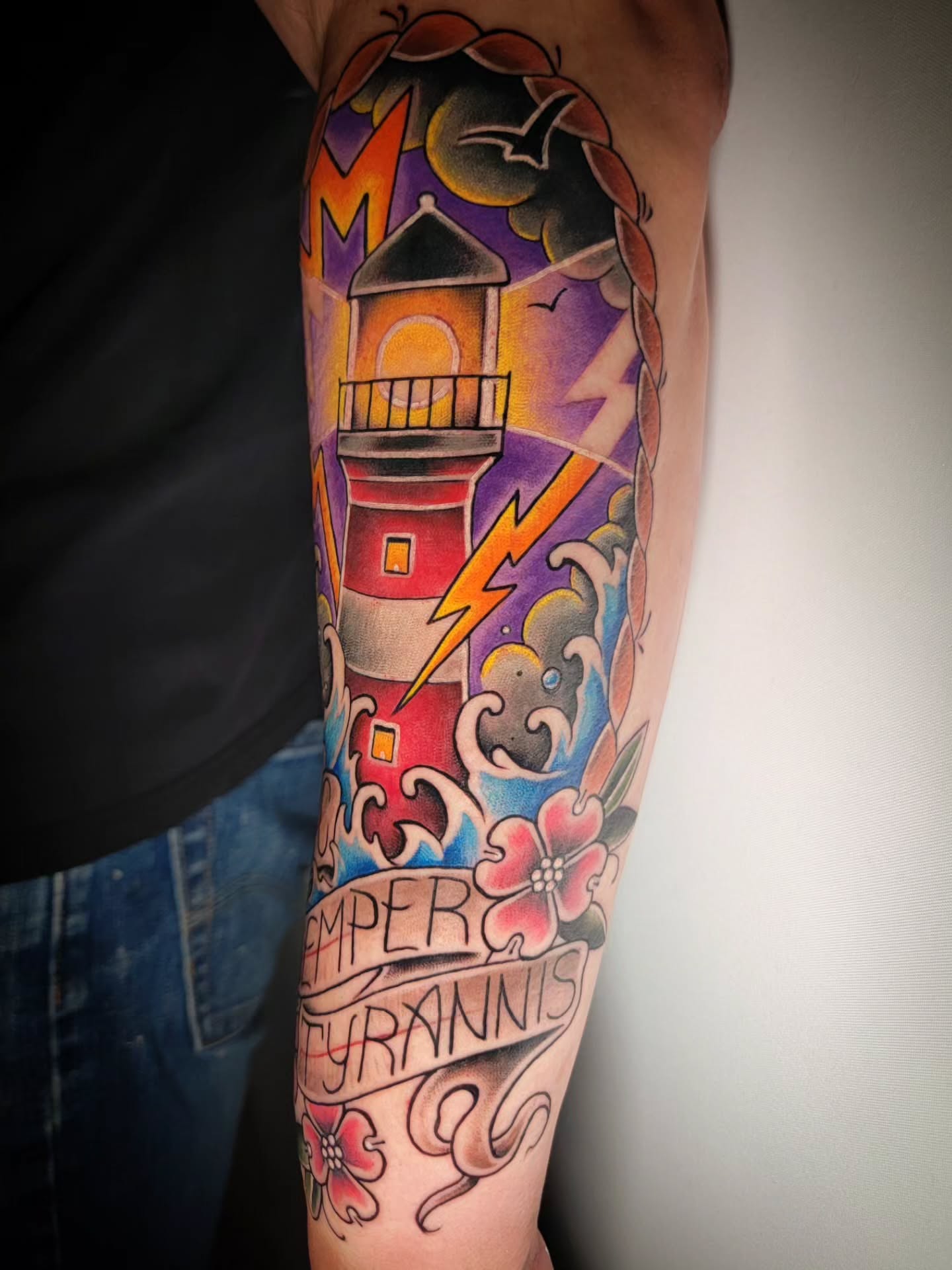 Lighthouse and lightning American traditional tattoo on the forearm by Randyz Tattyz