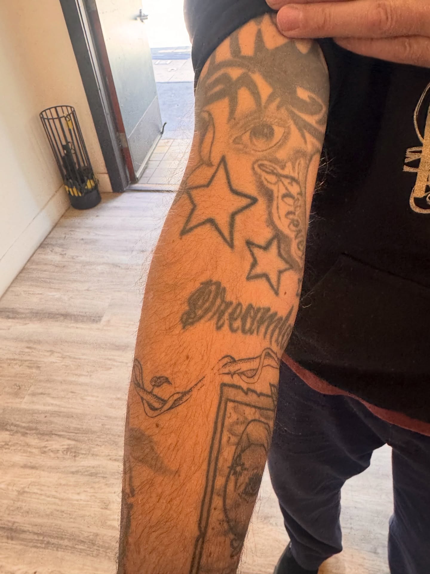 Stars and eye black and grey tattoo on the forearm by Sam Padilla