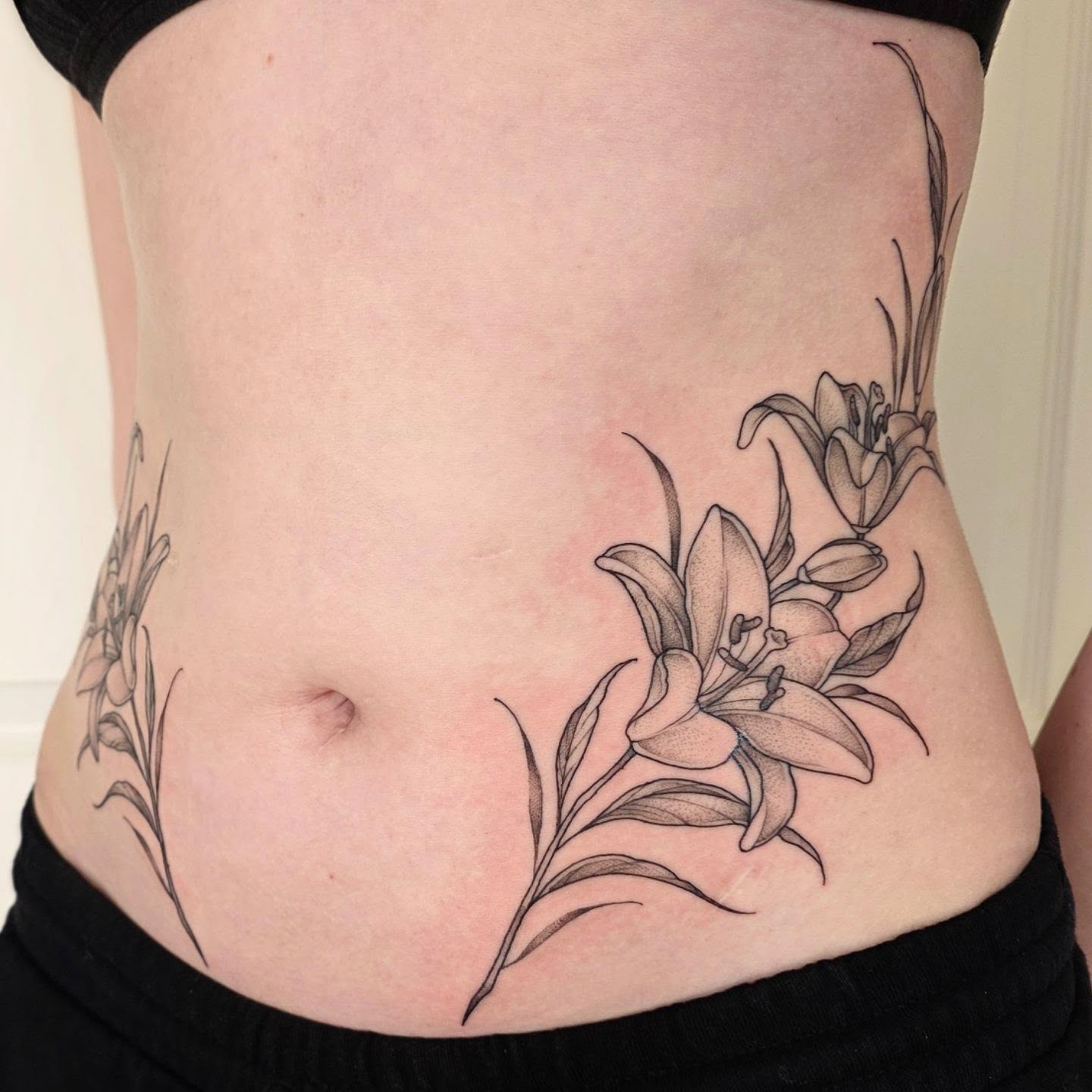 Lilies black and grey tattoo on the torso by Dani Bond