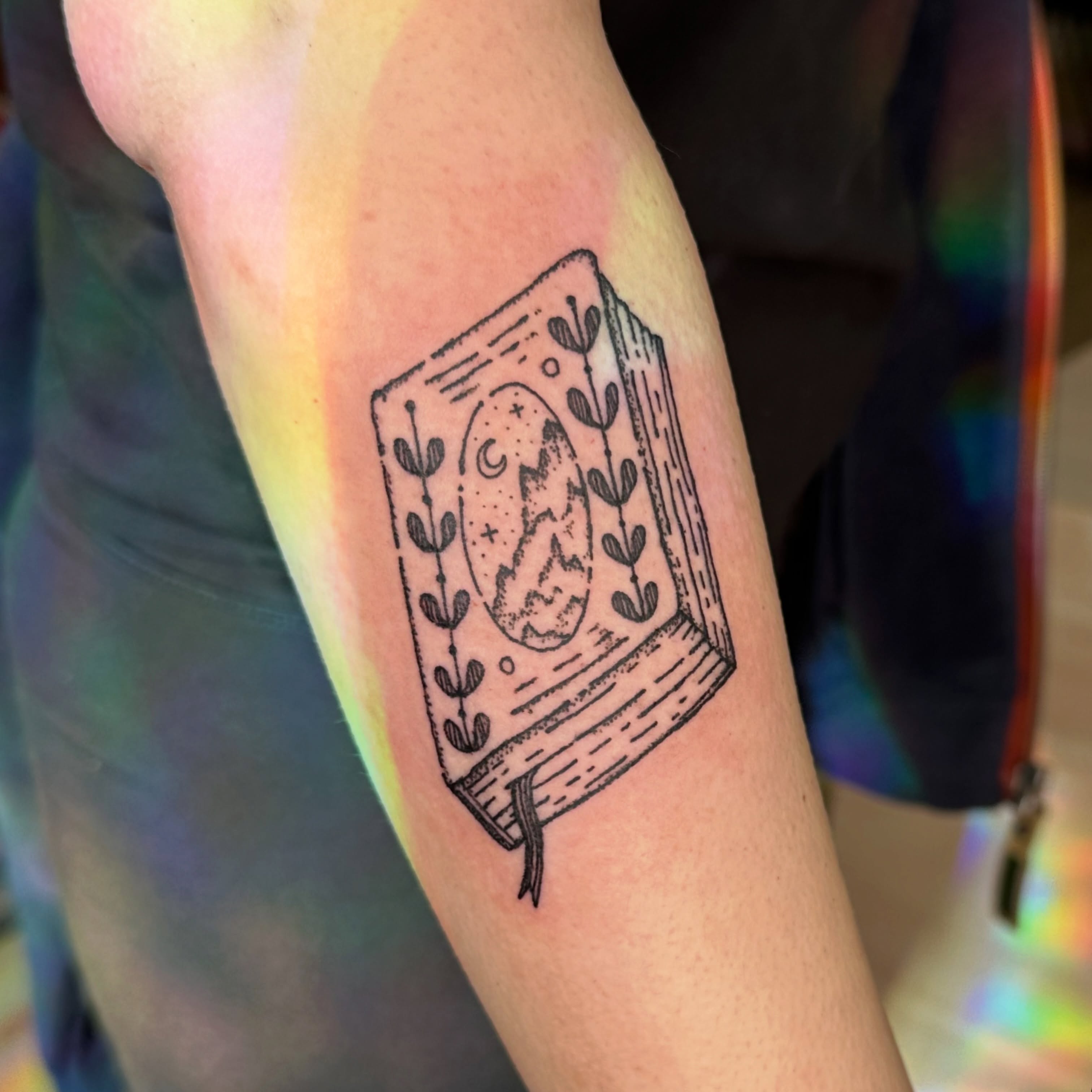 Book with moon and stars black and grey tattoo on the forearm by Fleur ๐ฅ