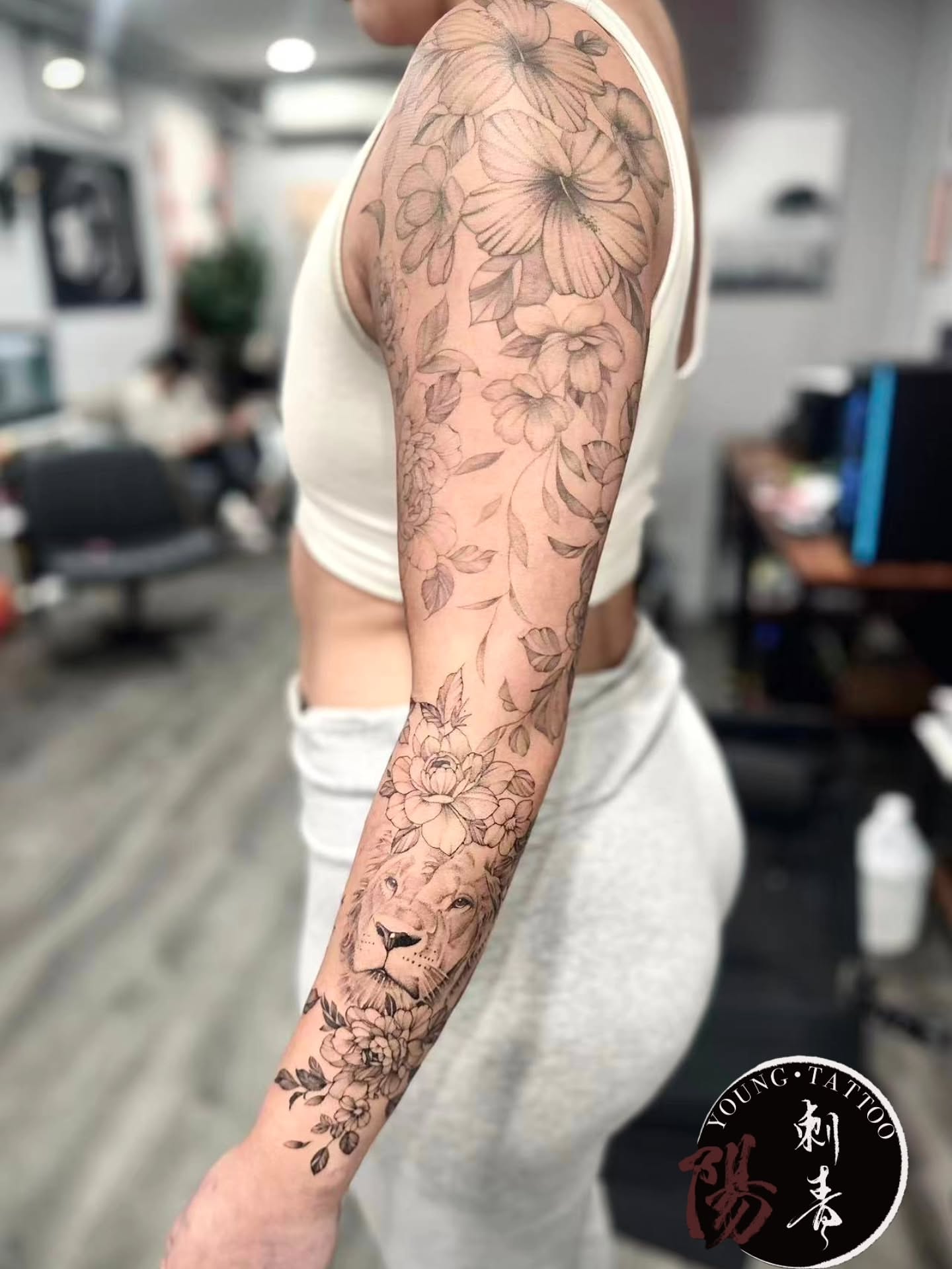 Lion and floral realism tattoo on the forearm by Ying