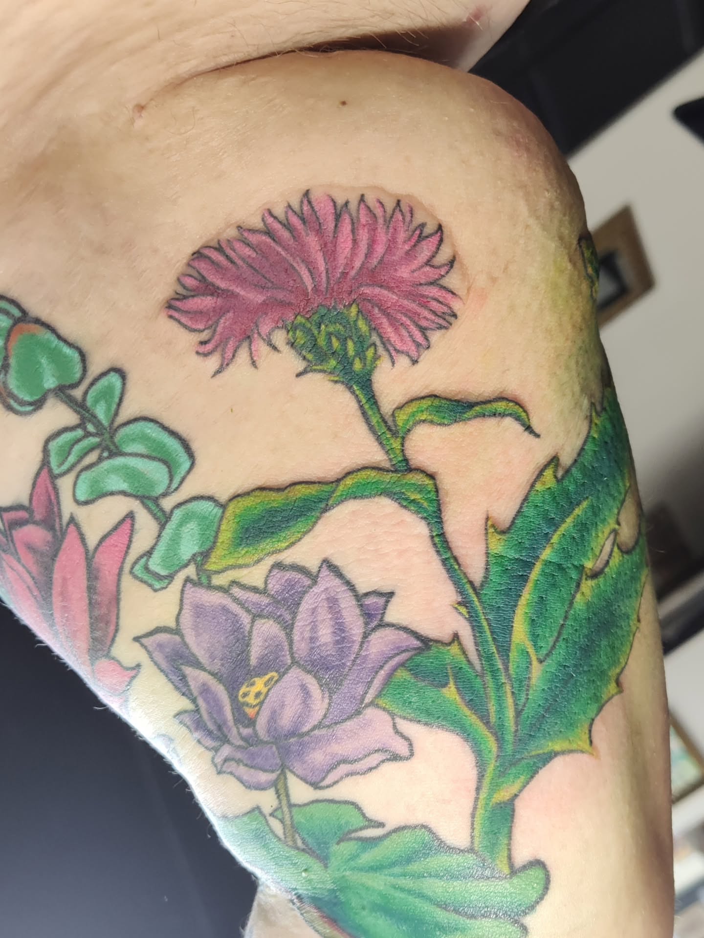 Floral arrangement realism tattoo on the upper arm by Mercury