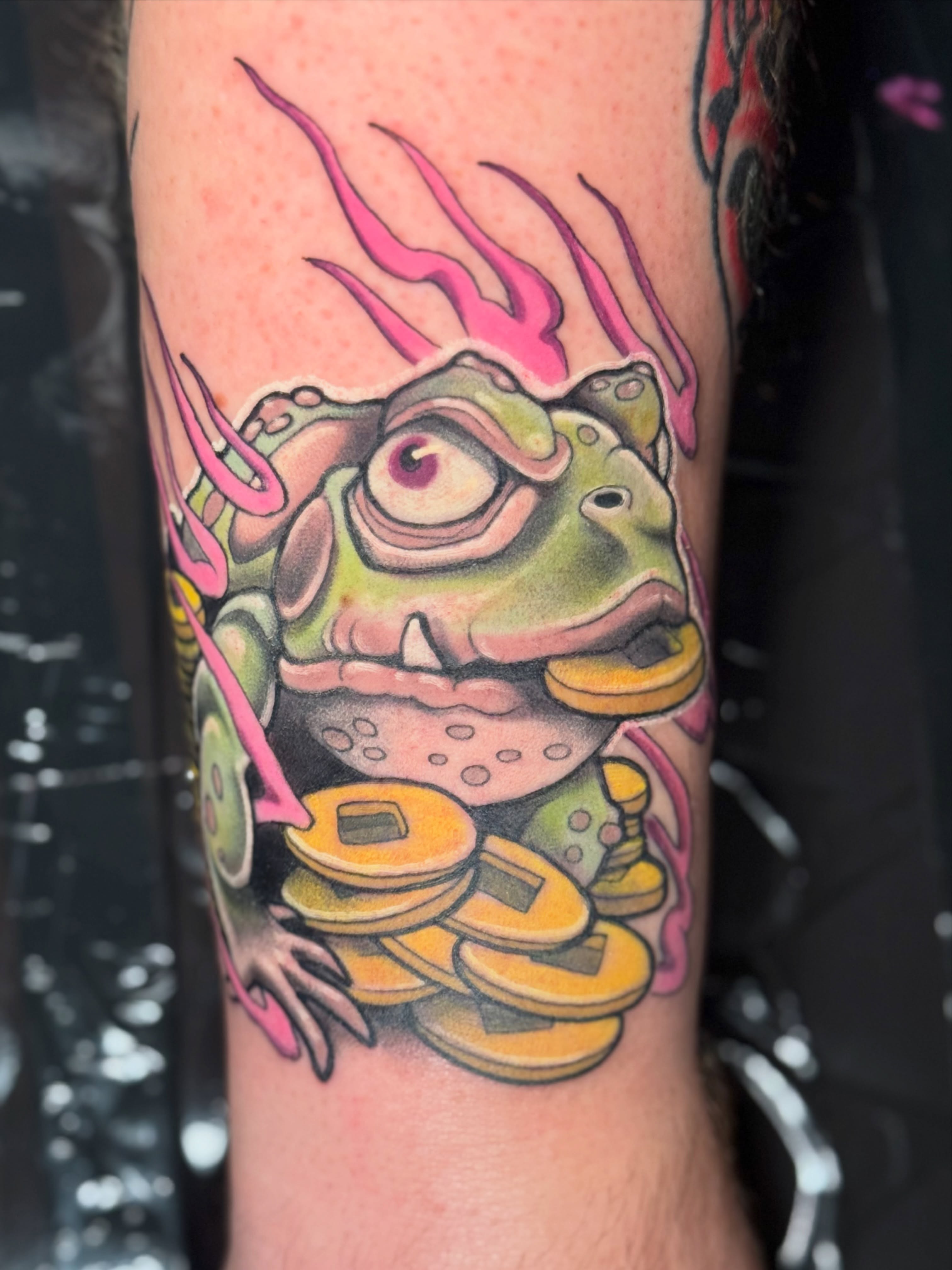 Frog with coins new school tattoo on the forearm by Steve Gentile Tattoos