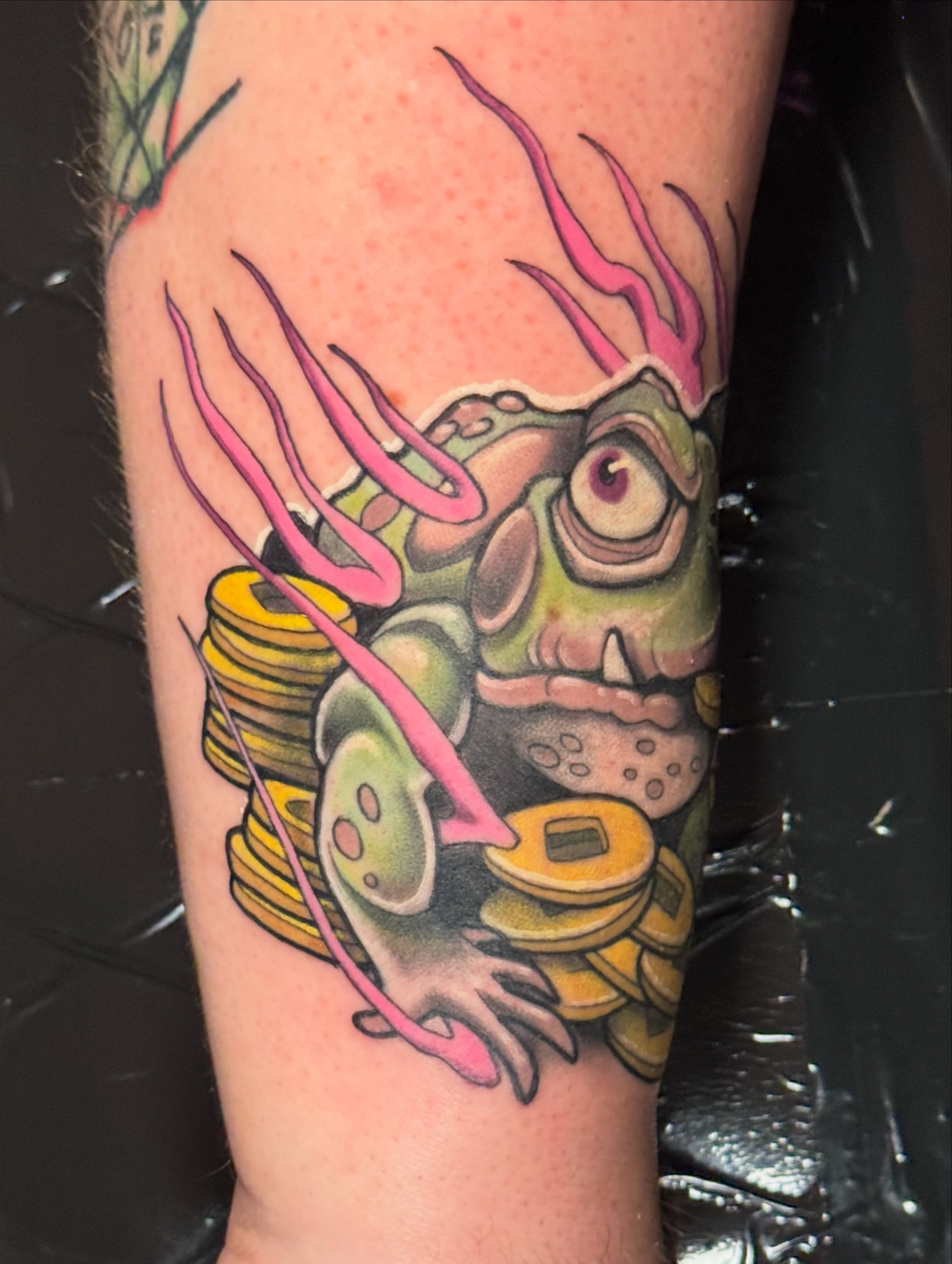 Frog with coins new school tattoo on the forearm by Steve Gentile Tattoos