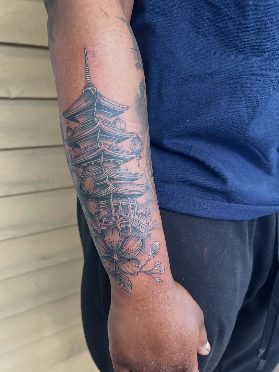 Pagoda and cherry blossoms Japanese tattoo on the forearm by Jai Woods