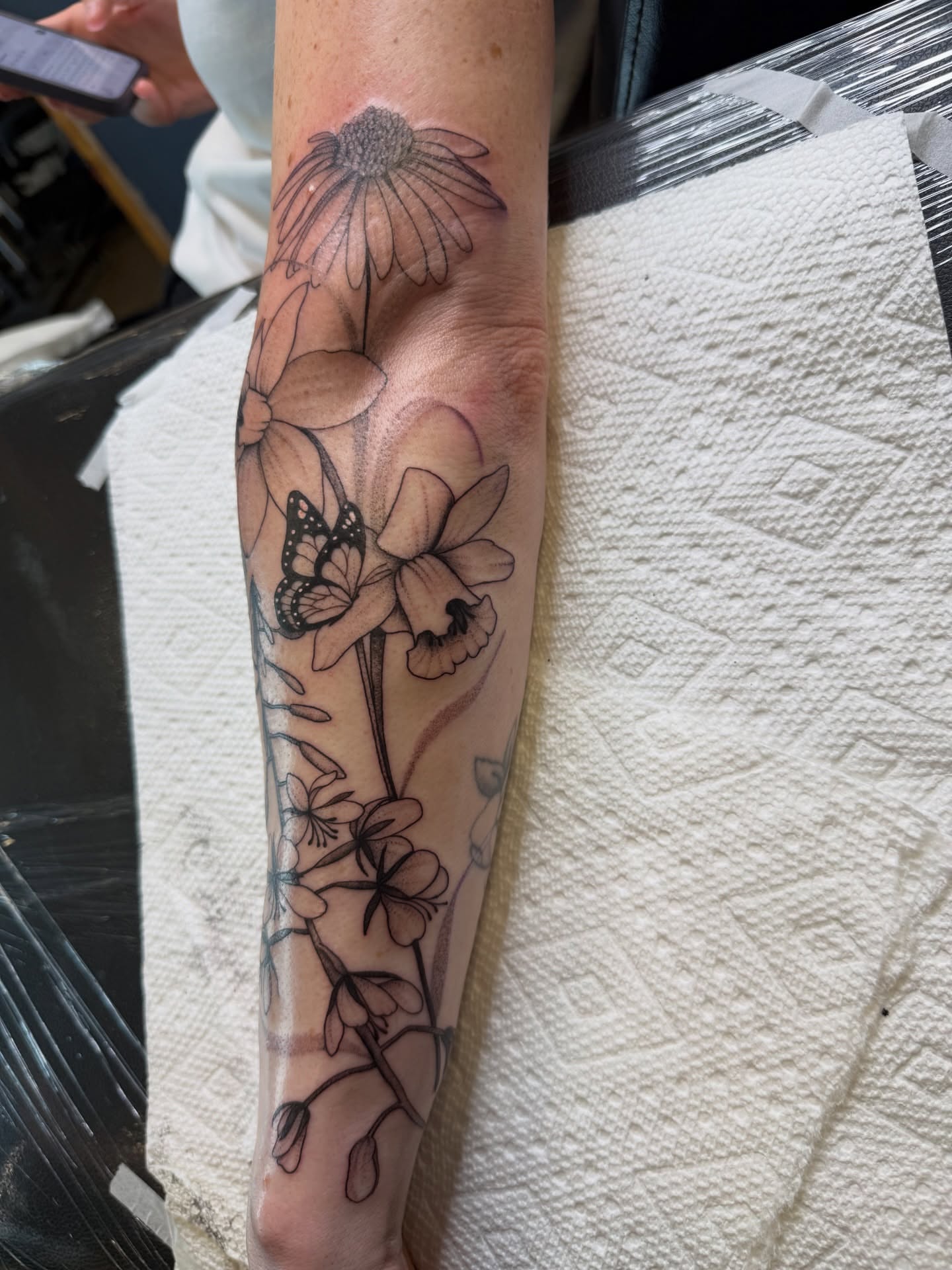 Flowers and butterfly black and grey tattoo on the forearm by WhoisLaineyTattoos