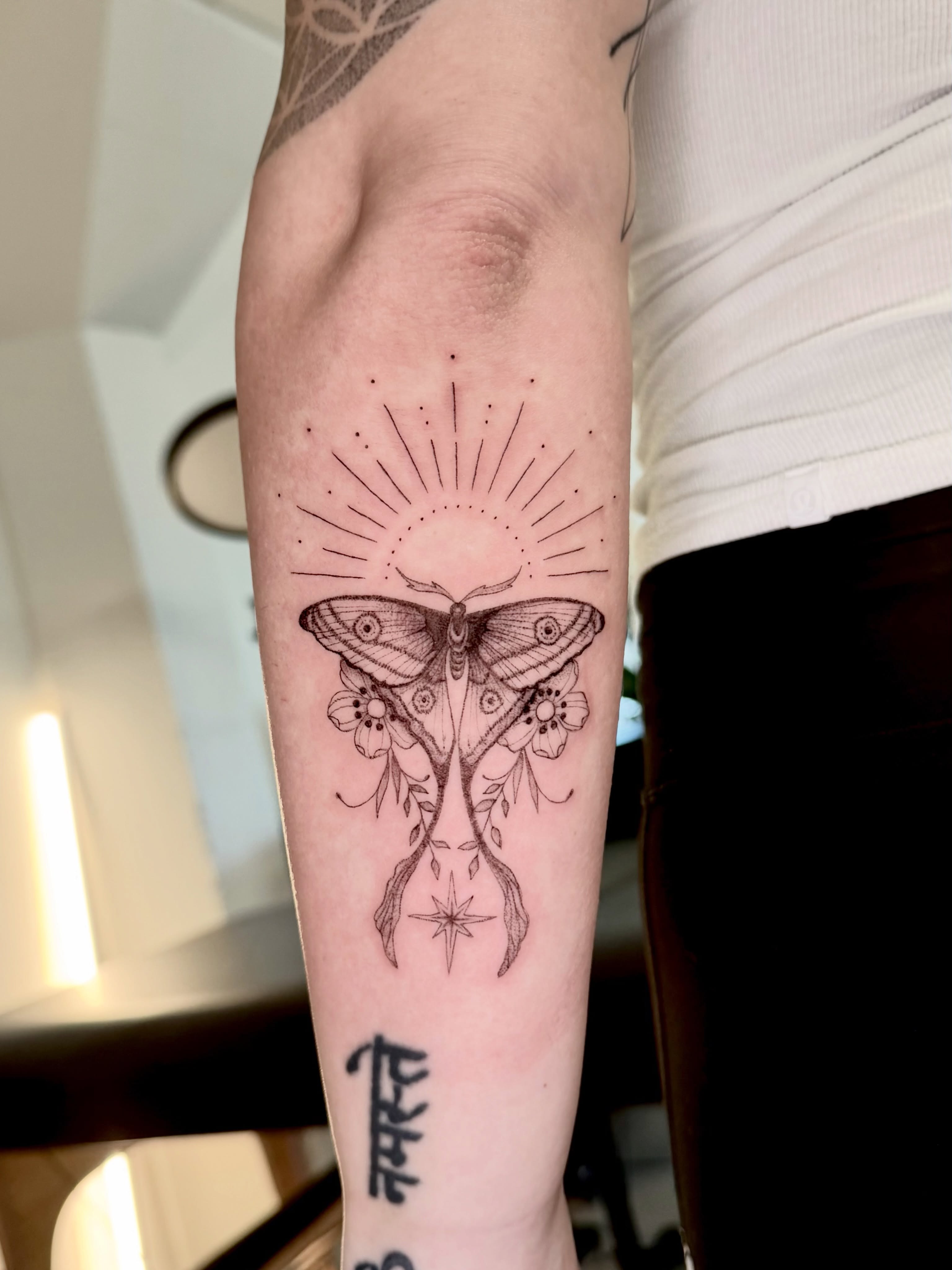 Moth and floral dotwork tattoo on the forearm by Anna