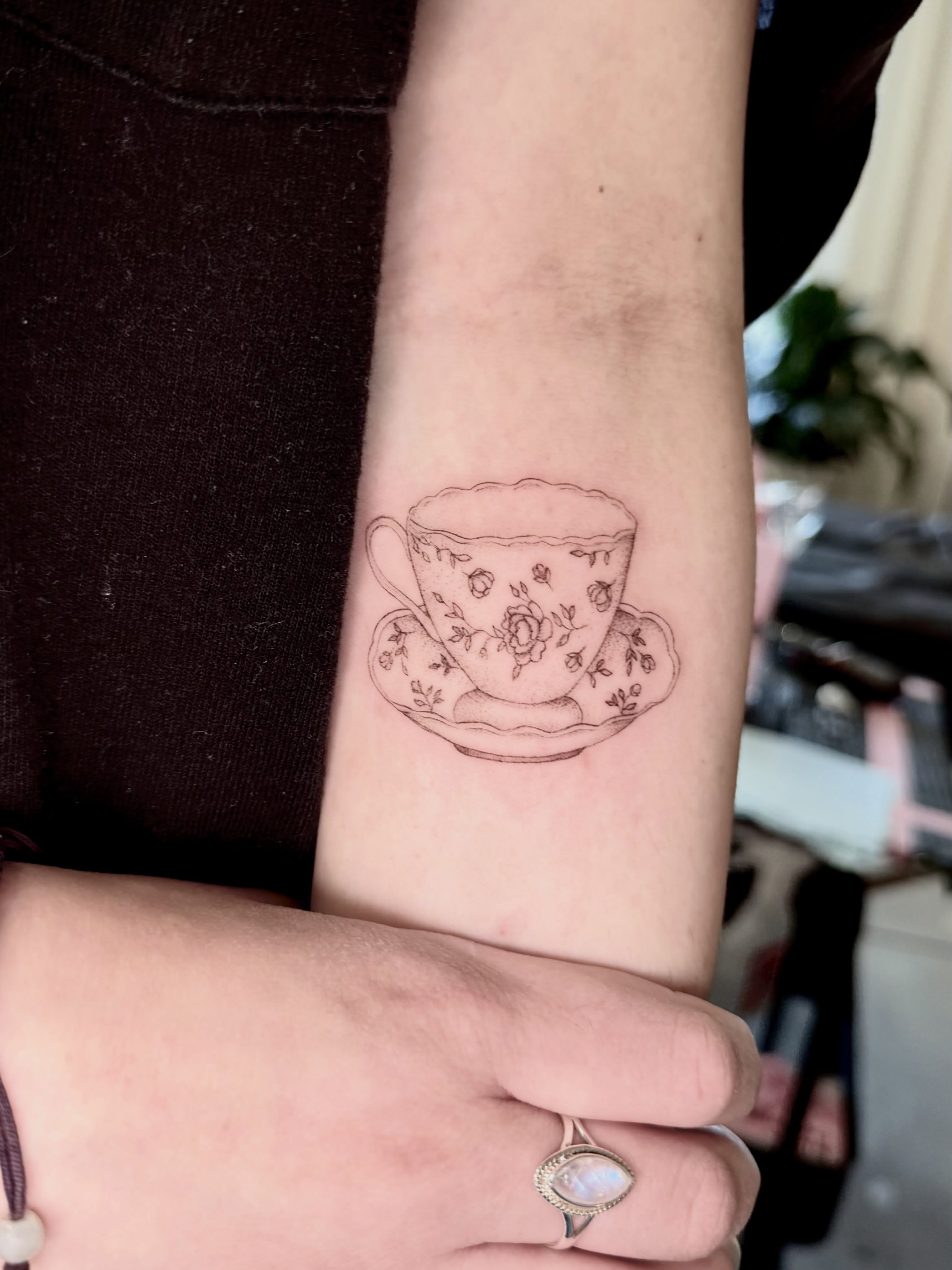 Teacup and saucer black and grey tattoo on the forearm by Anna