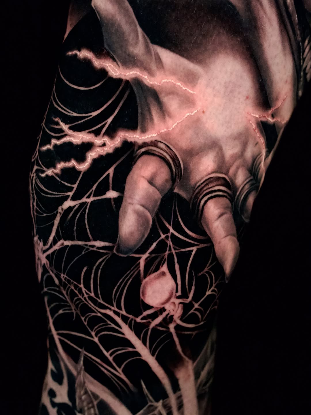 Hand with spiderweb and lightning blackwork tattoo on the forearm by April Lynn