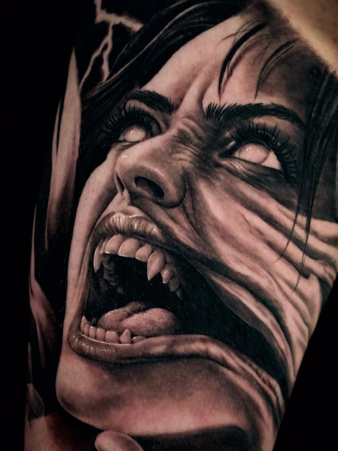 Screaming face with fangs realism tattoo on the forearm by April Lynn