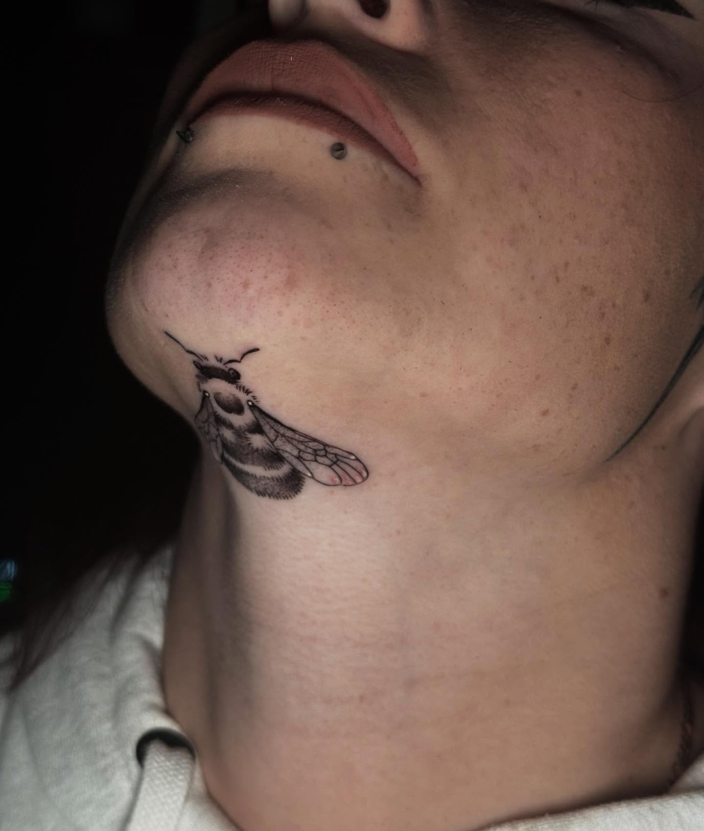 Bee realism tattoo on the neck by Mads Ink