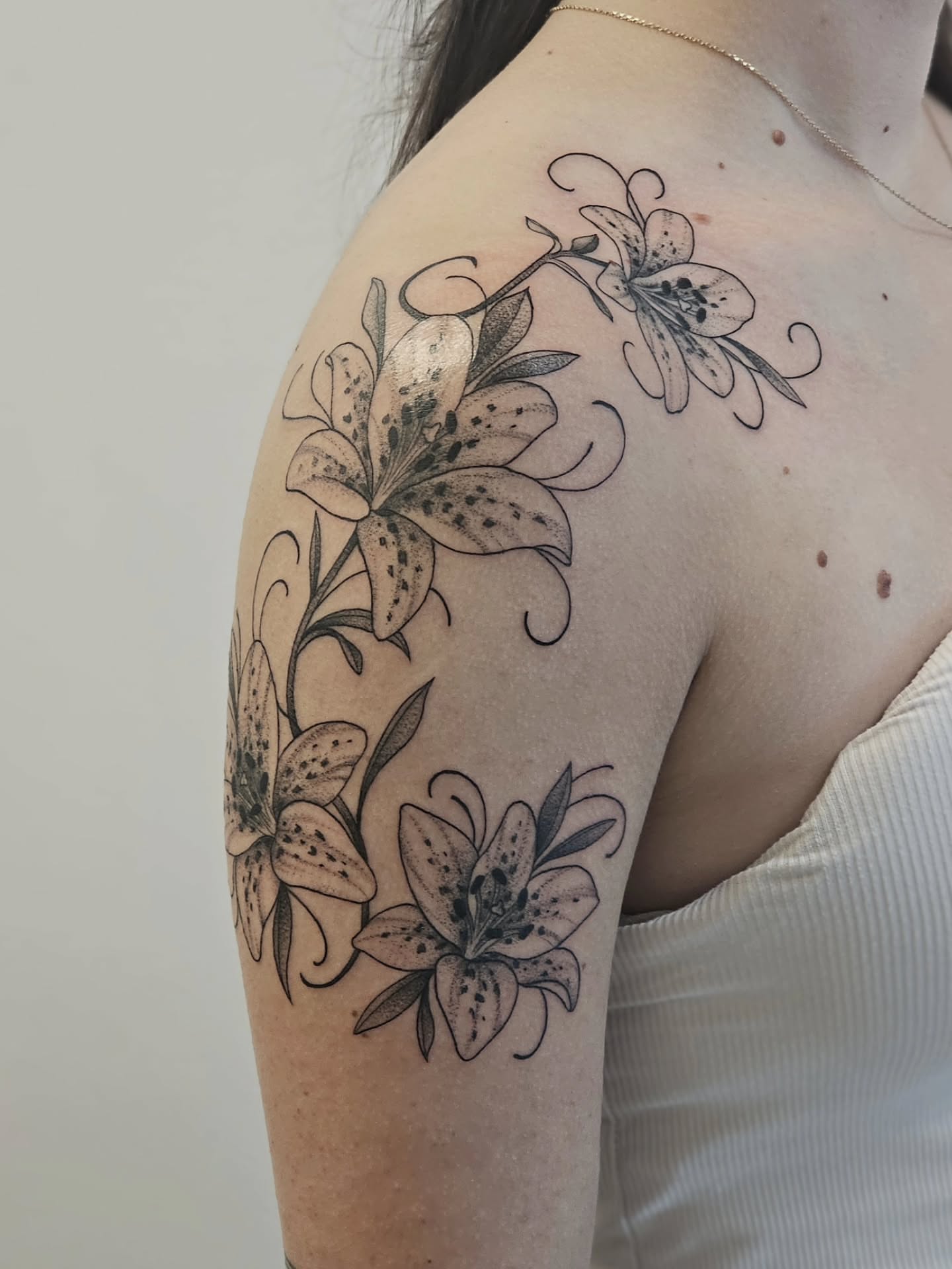 Lilies black and grey tattoo on the shoulder by Kylie Lund