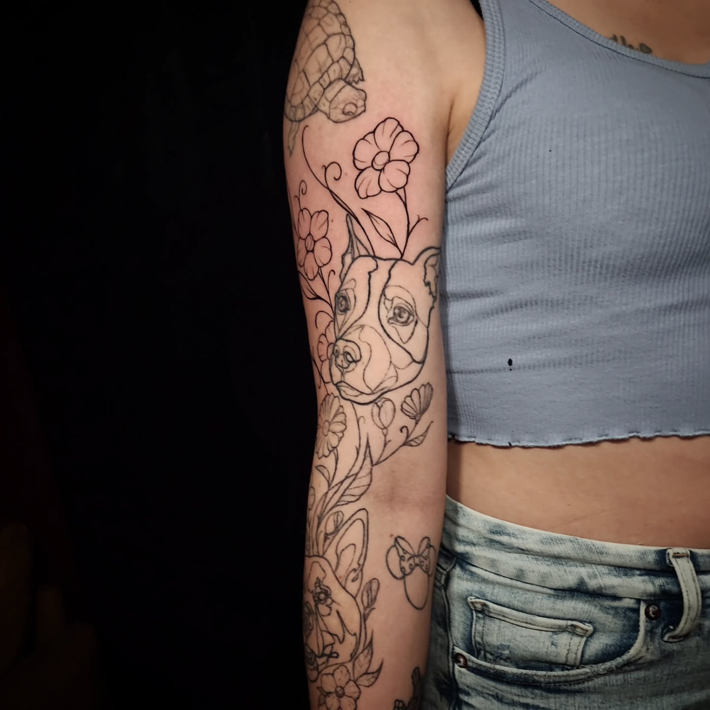 Dog with flowers black and grey tattoo on the forearm by Arthur Whitney Shail
