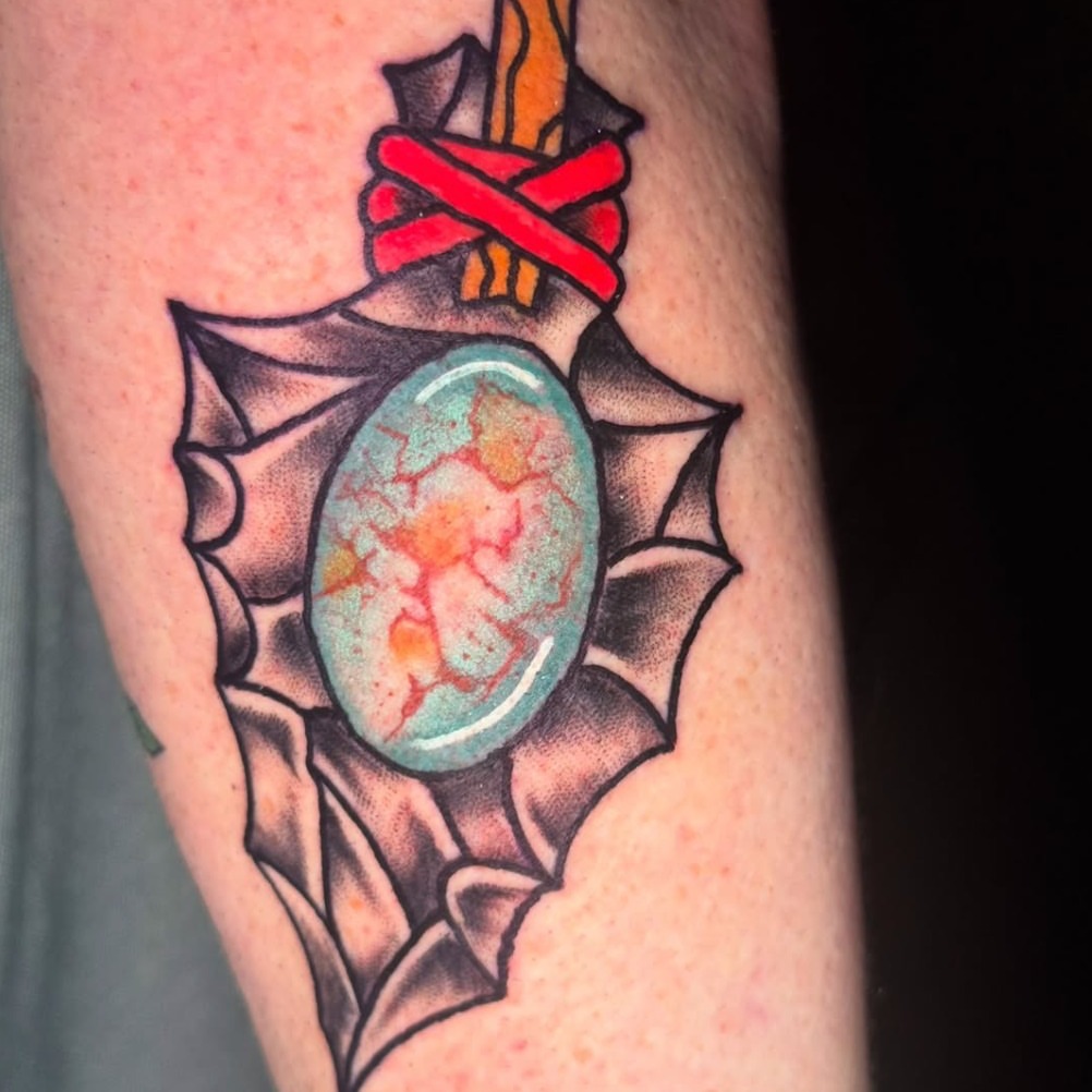 Gemstone sword American traditional tattoo on the forearm by Kenneth Gibson