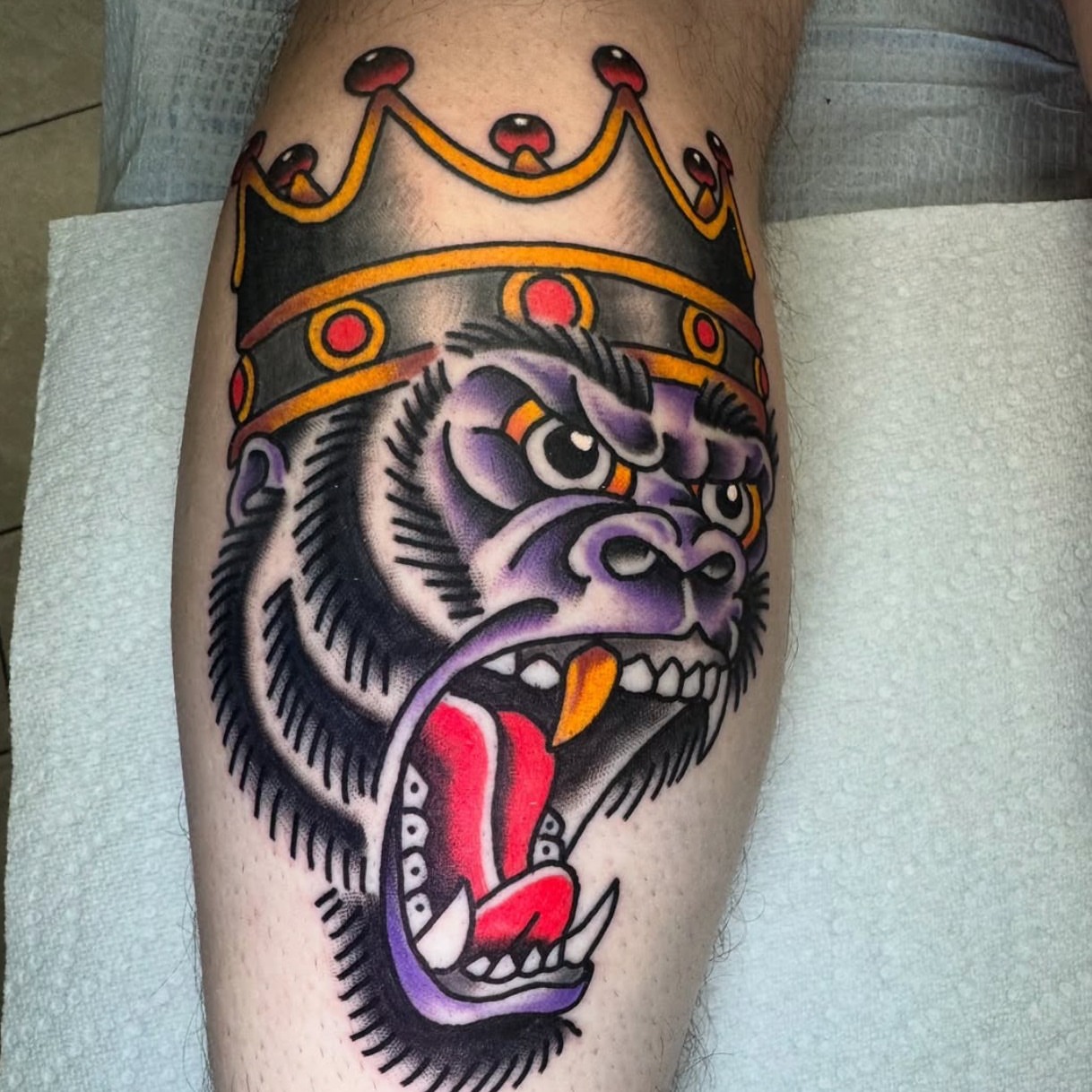 Gorilla wearing crown American traditional tattoo on the thigh by Kenneth Gibson