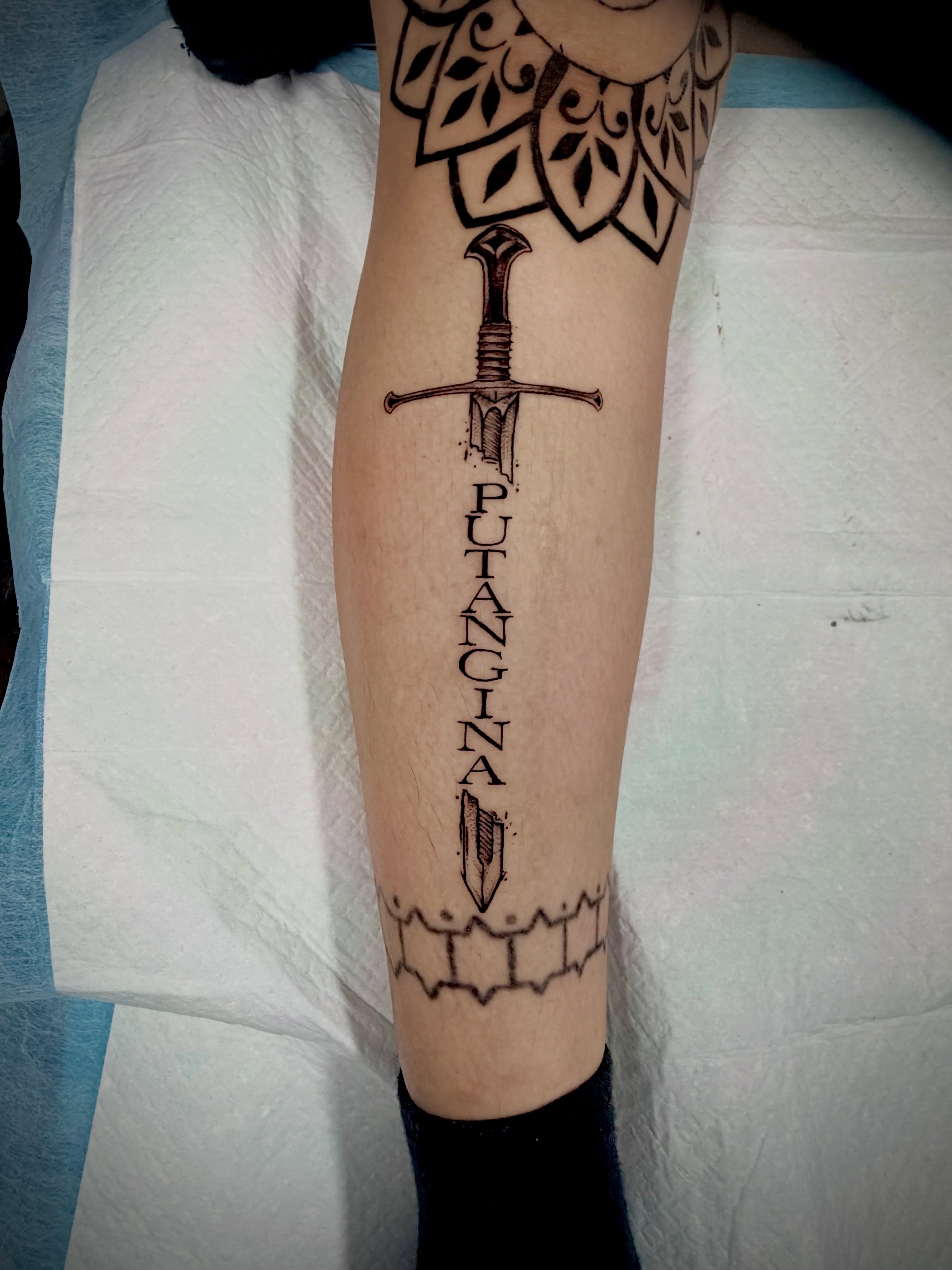 Sword and lettering black and grey tattoo on the forearm by John Ayson, Murrieta, California