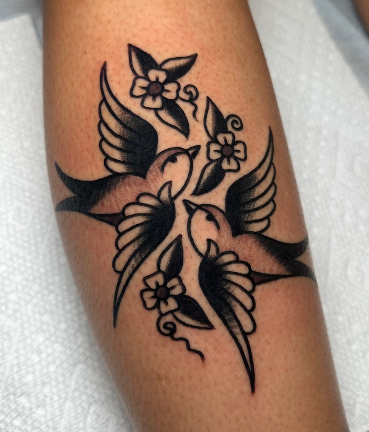 Birds and flowers black and grey tattoo on the forearm by Zahra Niedermann
