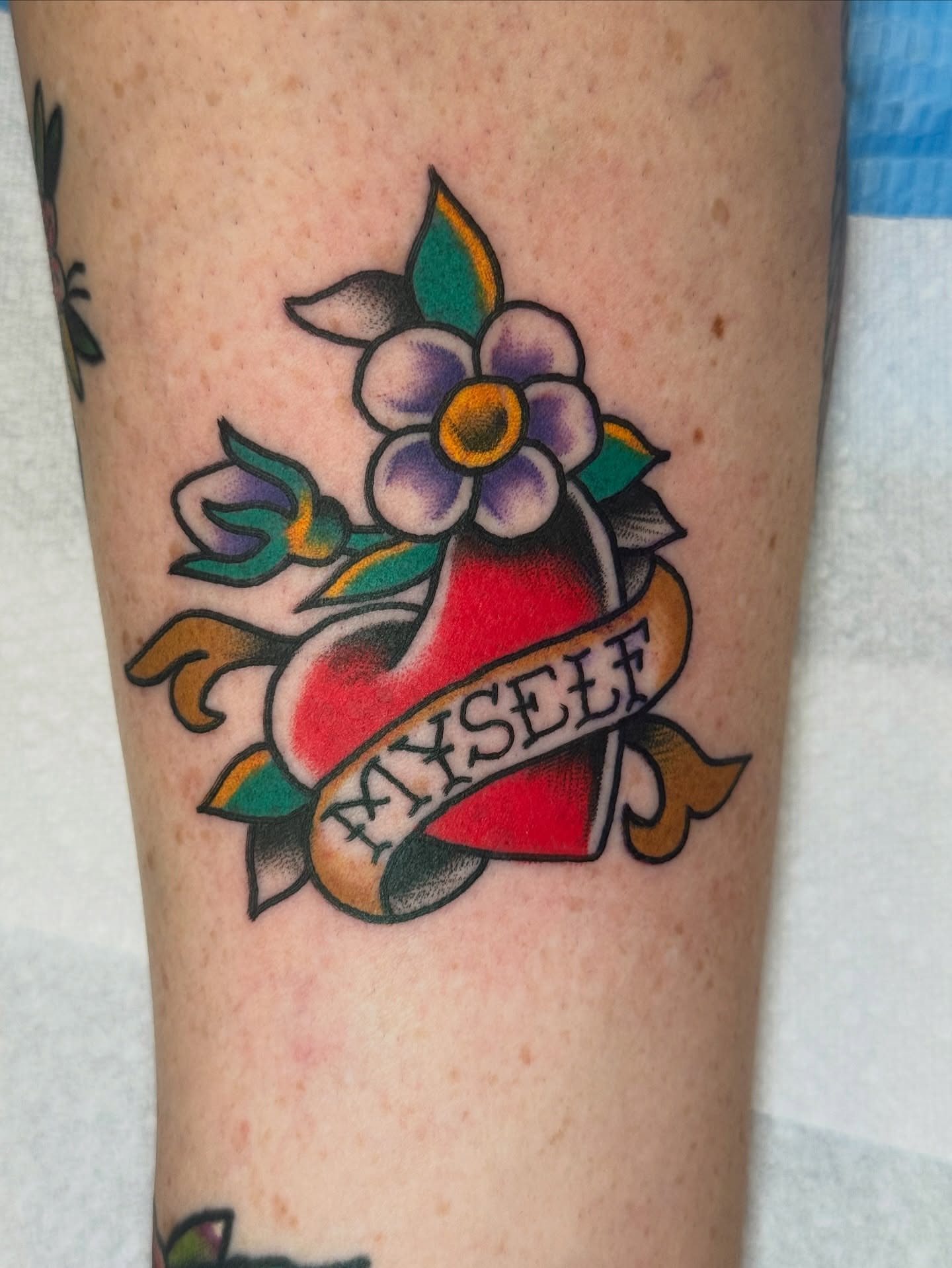 Heart with flower American traditional tattoo on the forearm by Kenneth Gibson