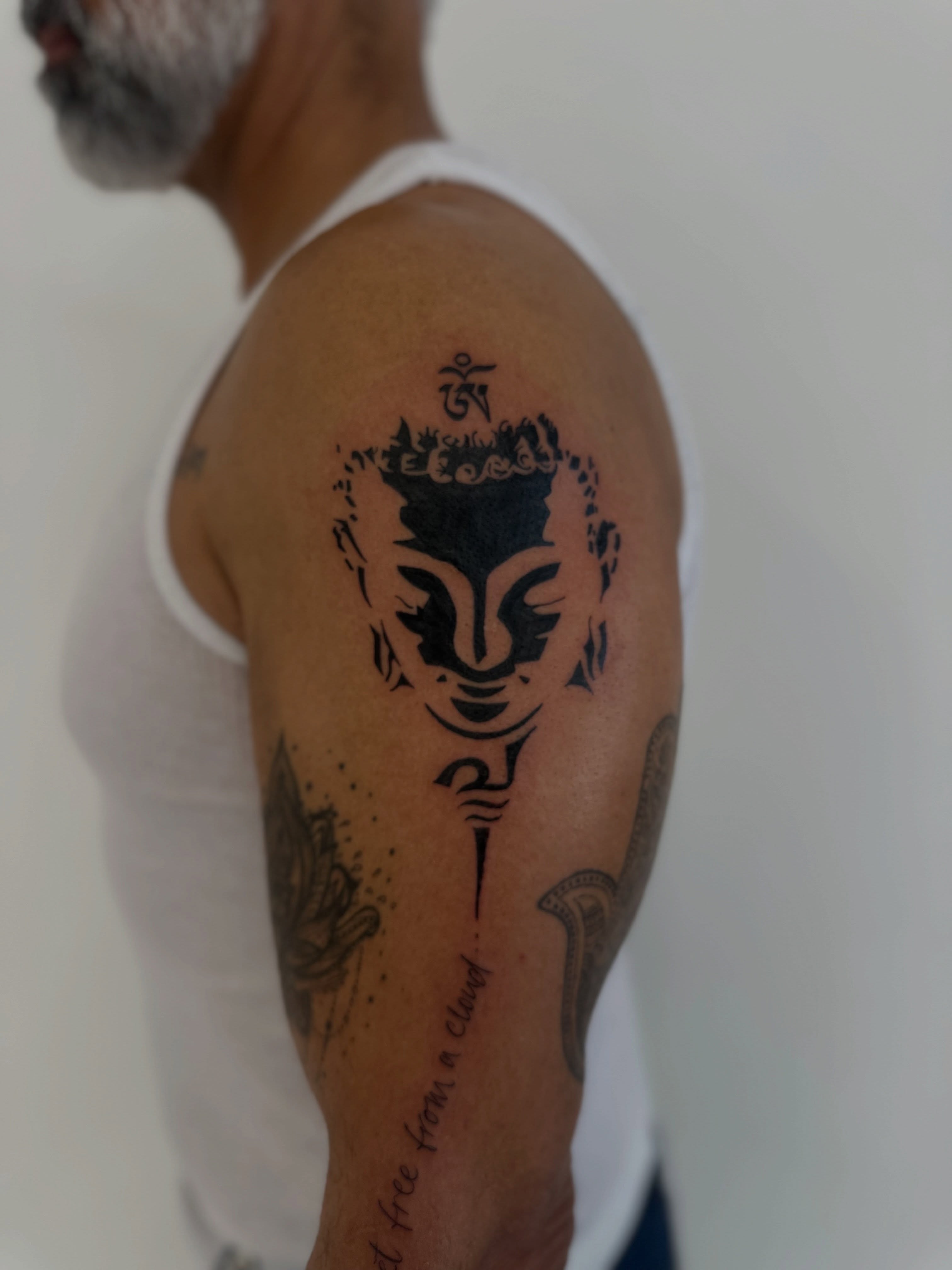 Buddha head black and grey tattoo on the shoulder by Ric Castellon Tattoo Artist, Los Angeles, California