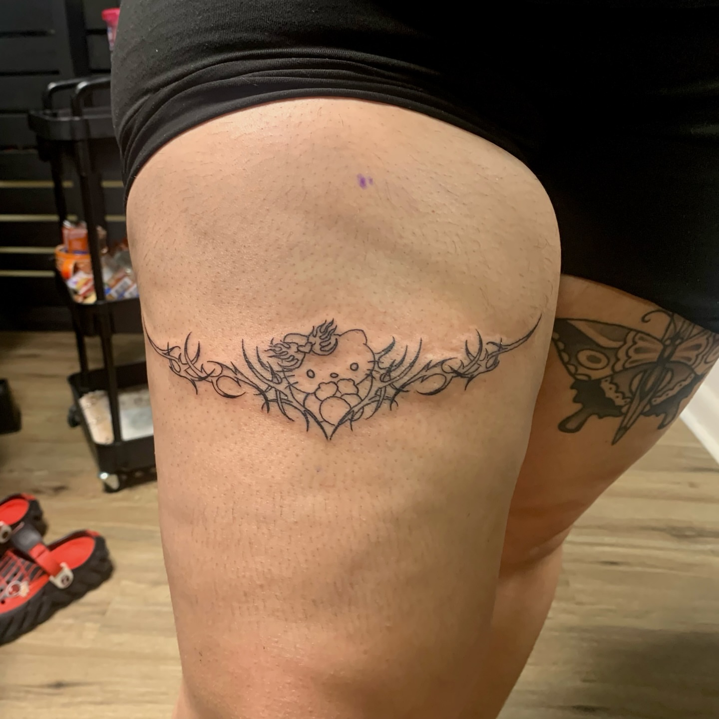 Hello Kitty black and grey tattoo on the thigh by Sam Ingalls