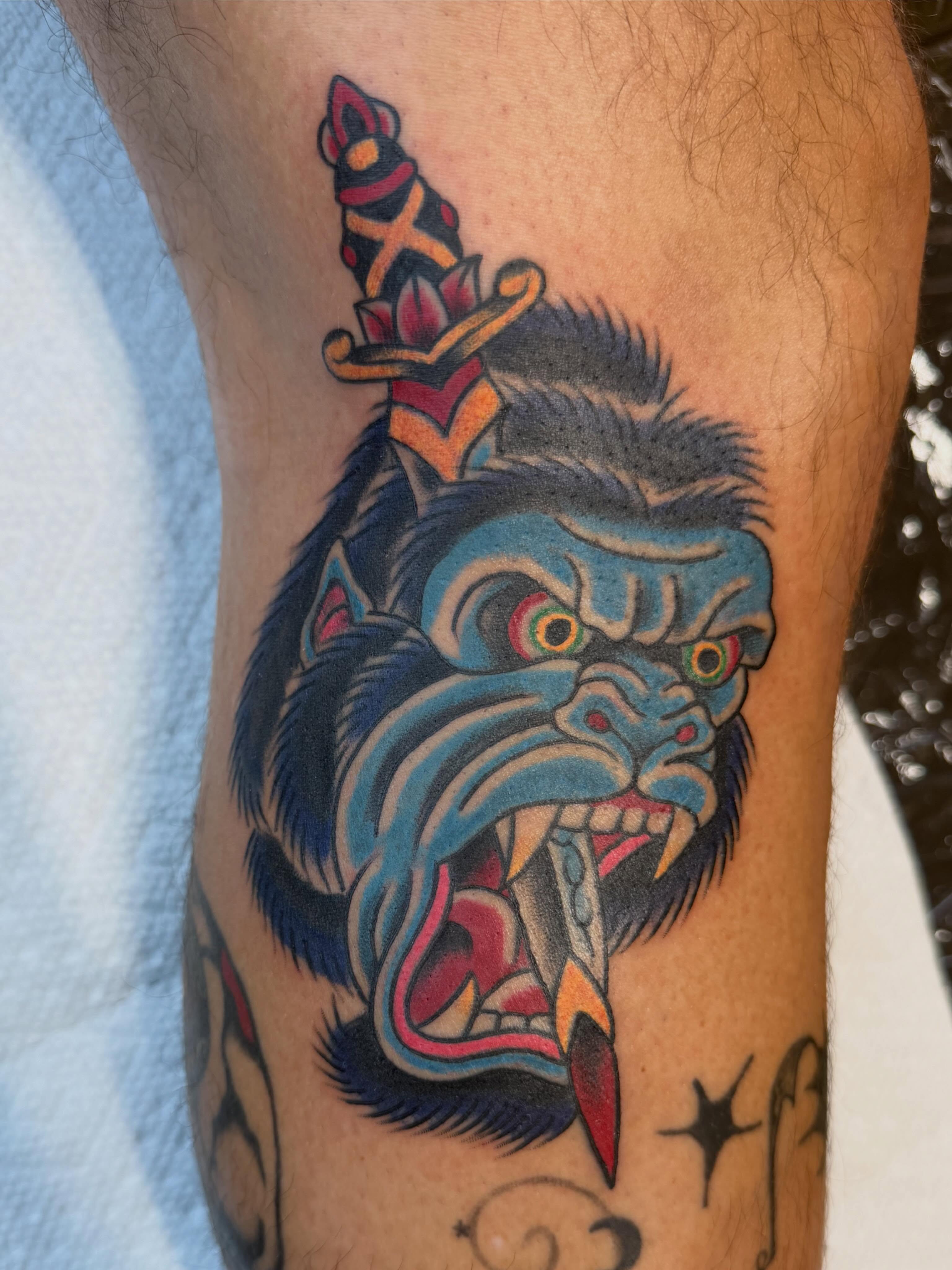 Wolf head with dagger American traditional tattoo on the forearm by Evan Voelker