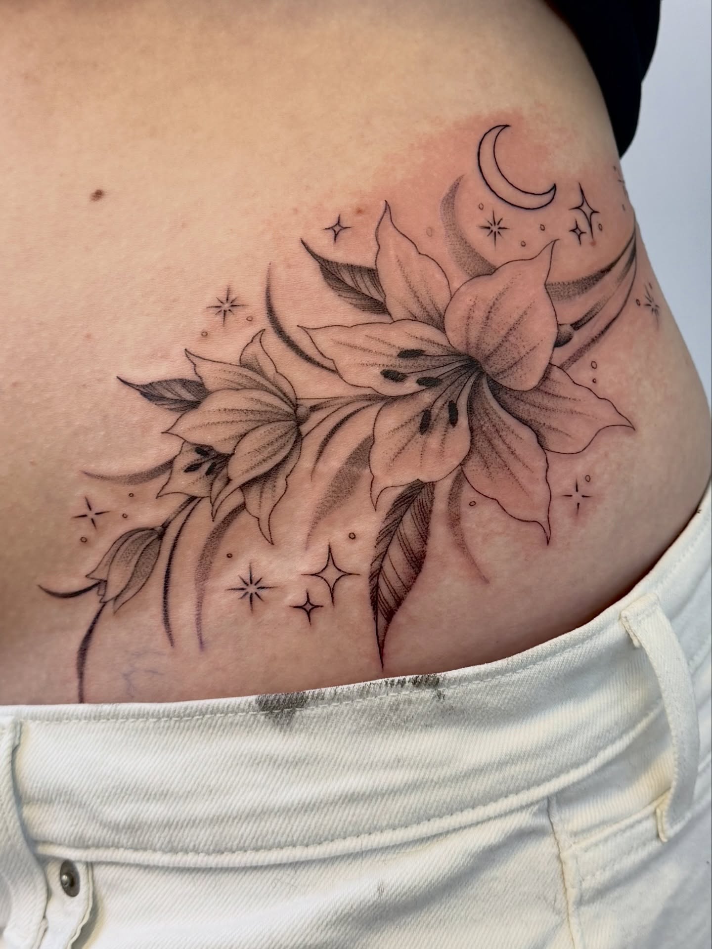 Lily and stars black and grey tattoo on the ribs by @nudylicioustattoos