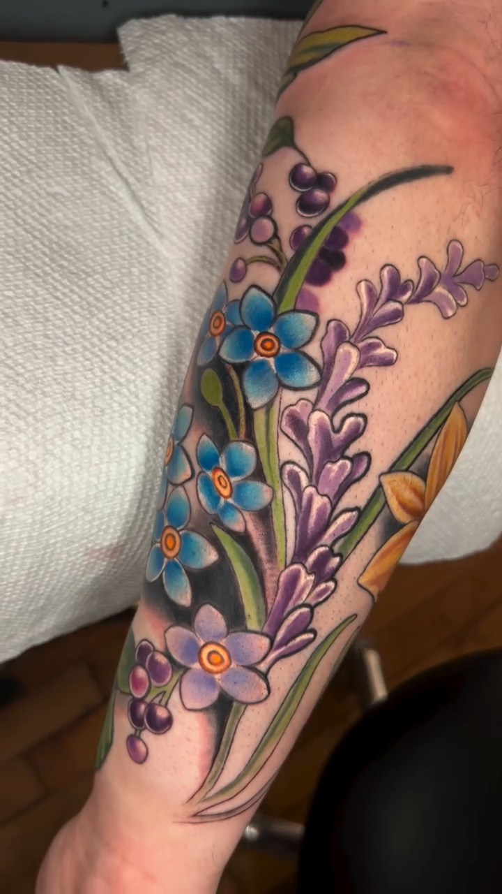 Floral arrangement with various flowers watercolor tattoo on the forearm by High Vibrations