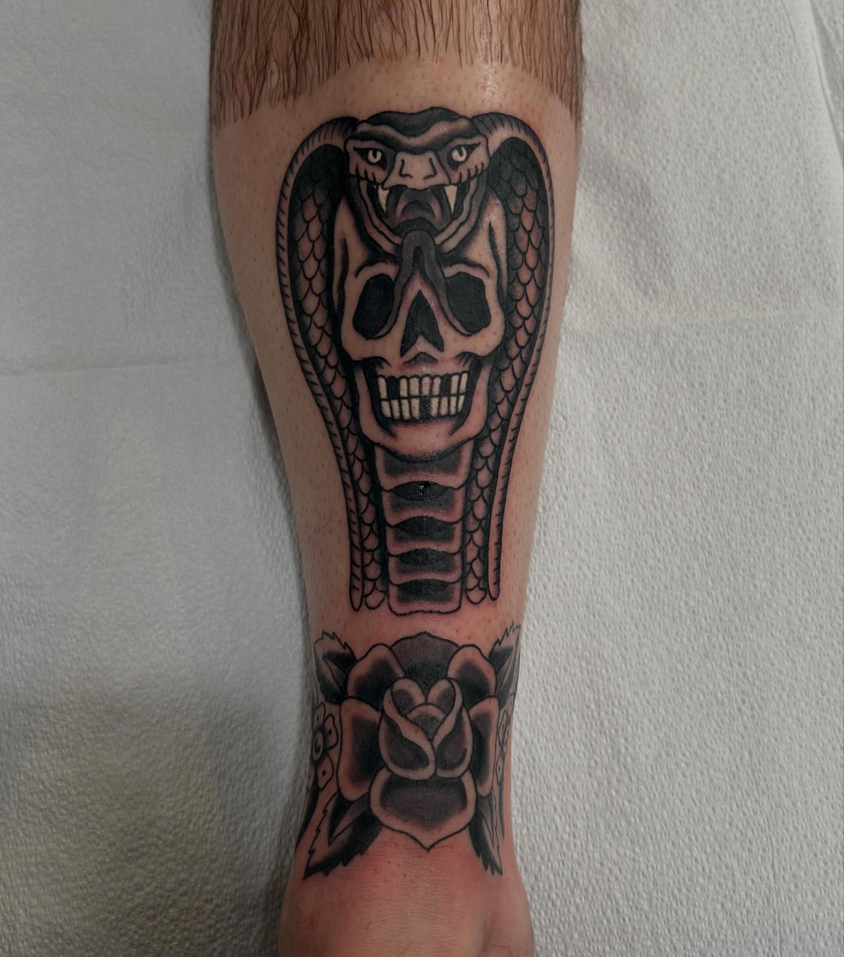 Snake and skull black and grey tattoo on the forearm by Donny