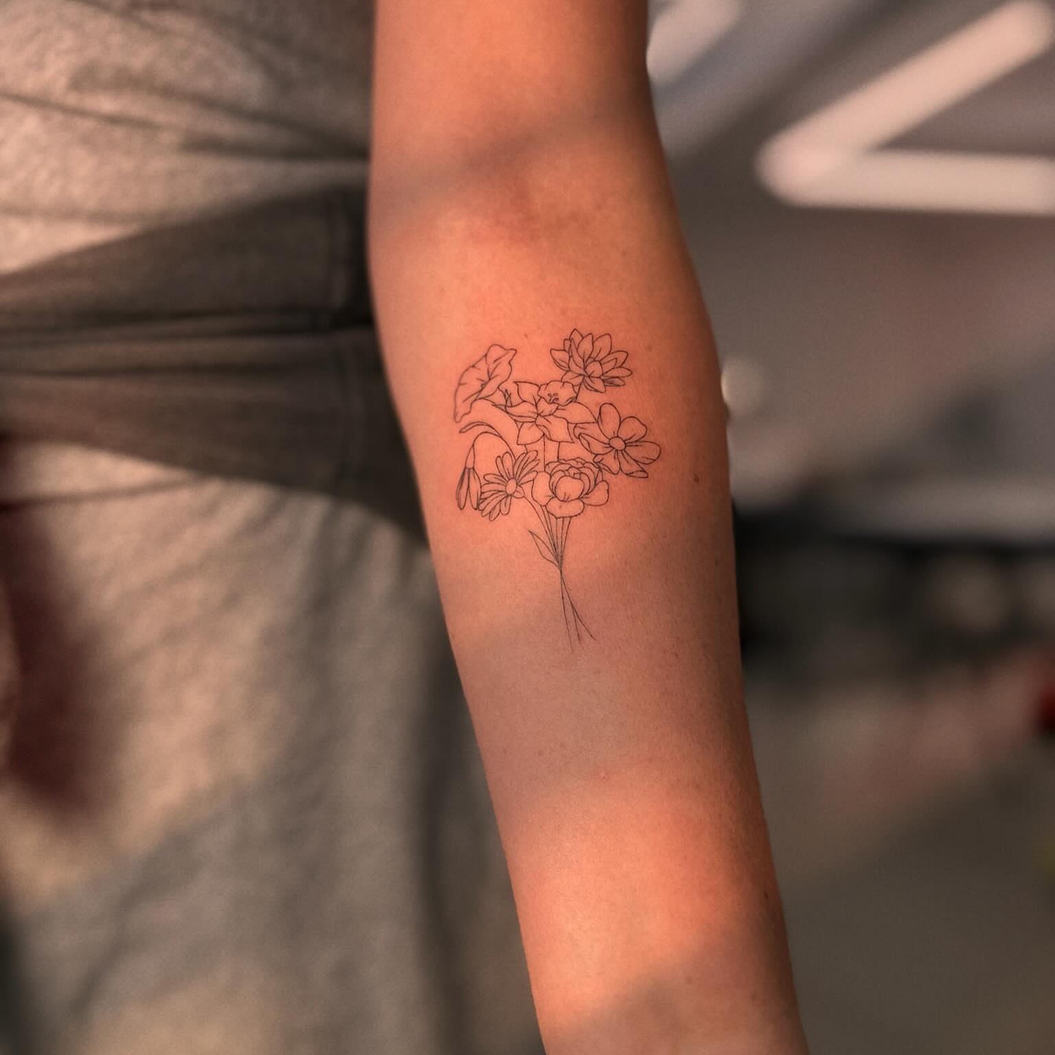 Flower bouquet fine line tattoo on the forearm by Ellie