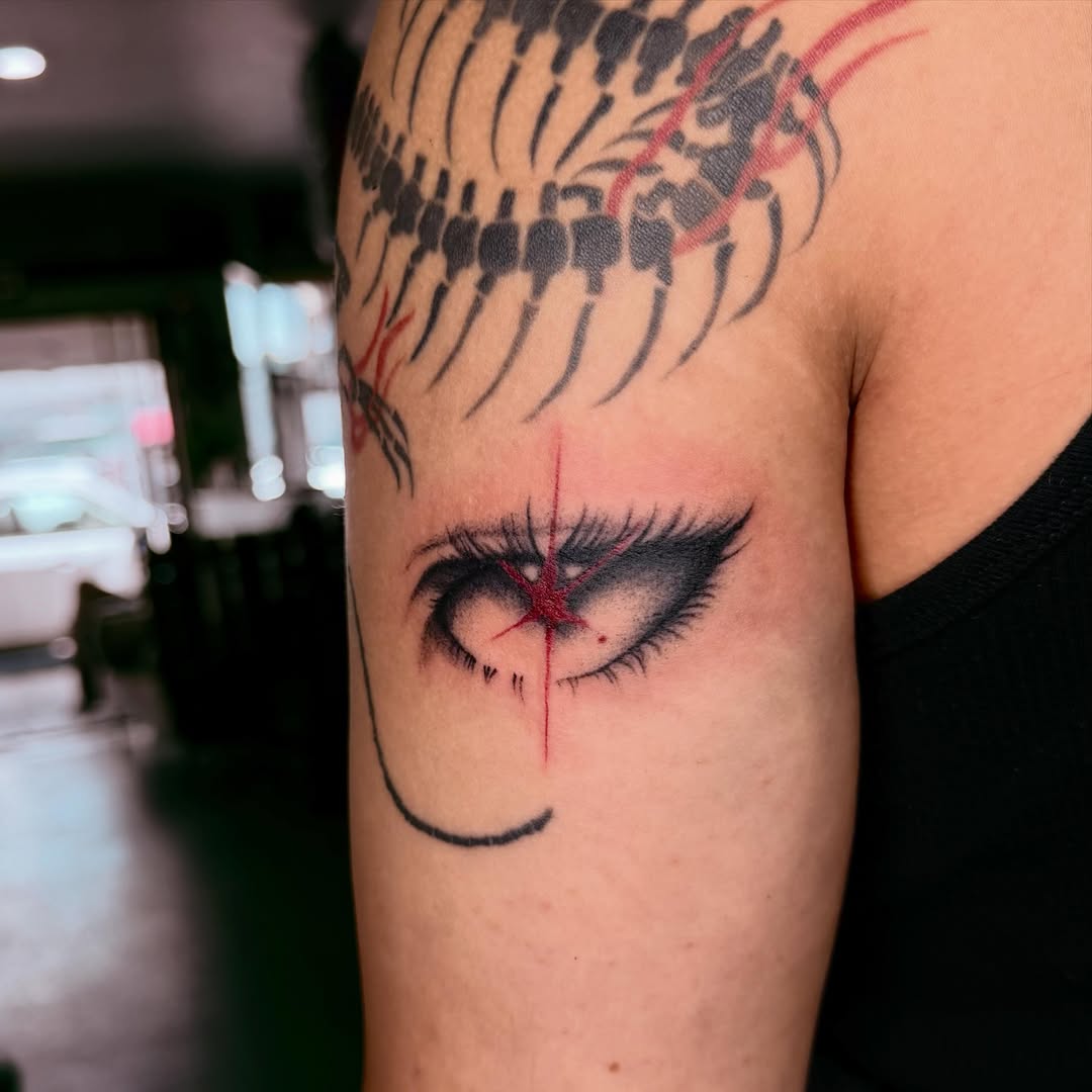 Stylized eye with red accents blackwork tattoo on the forearm by savannah