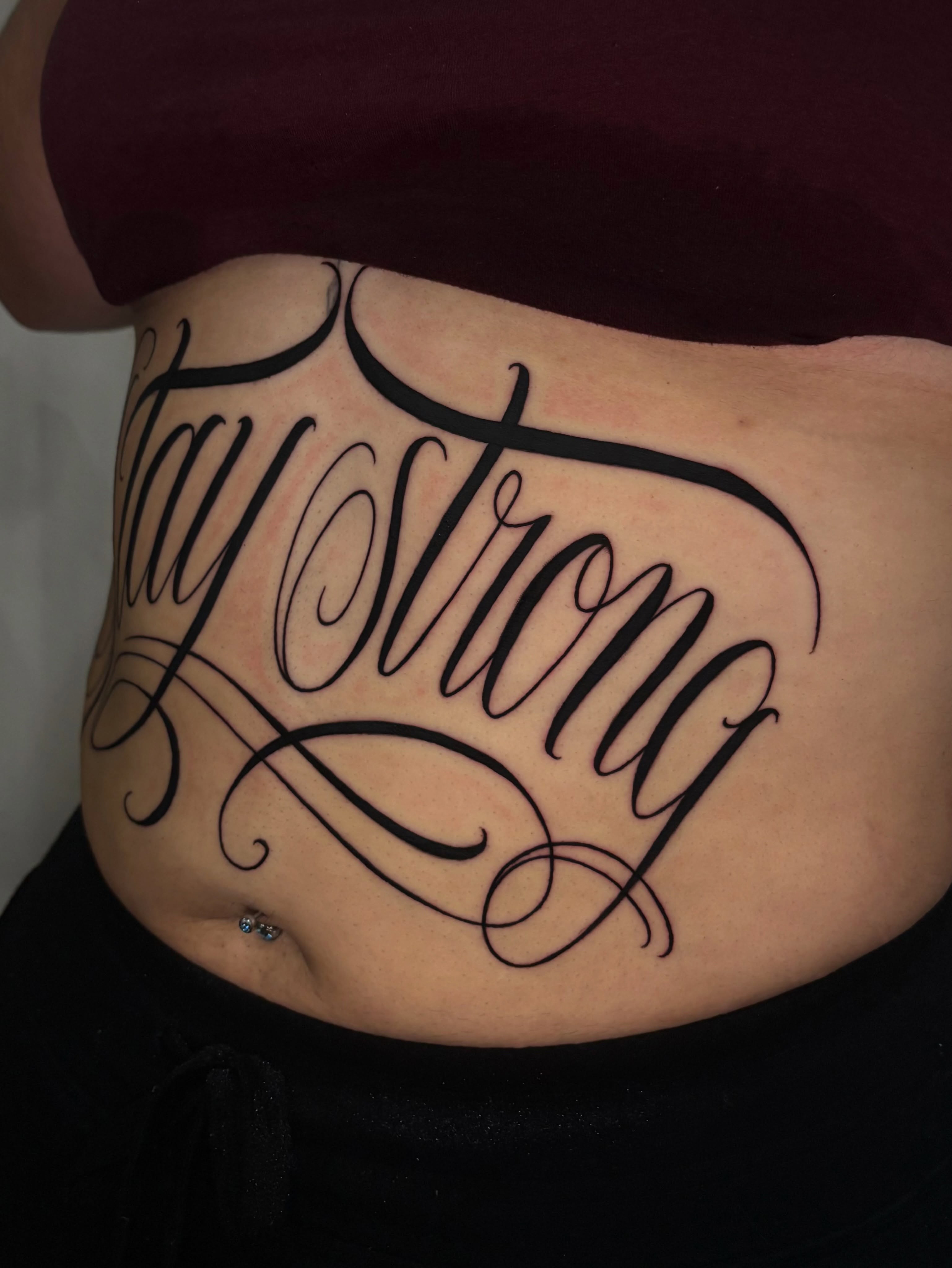 Stay strong lettering script tattoo on the torso by Osiel Rodriguez
