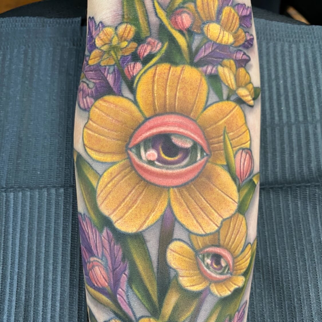 Eye and flowers illustrative tattoo on the forearm by Lindsay Hall