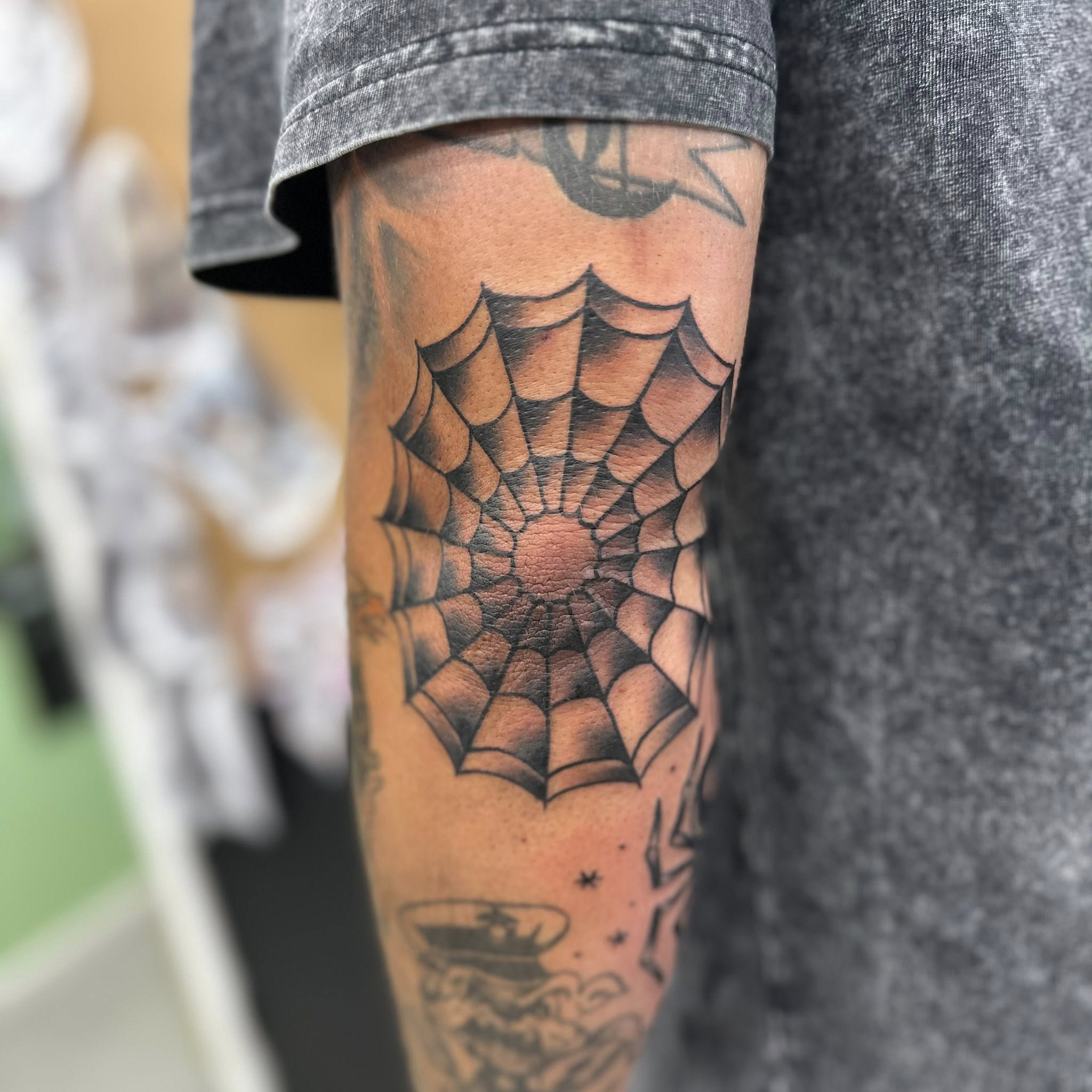 Spider web geometric tattoo on the forearm by Jon Anderson