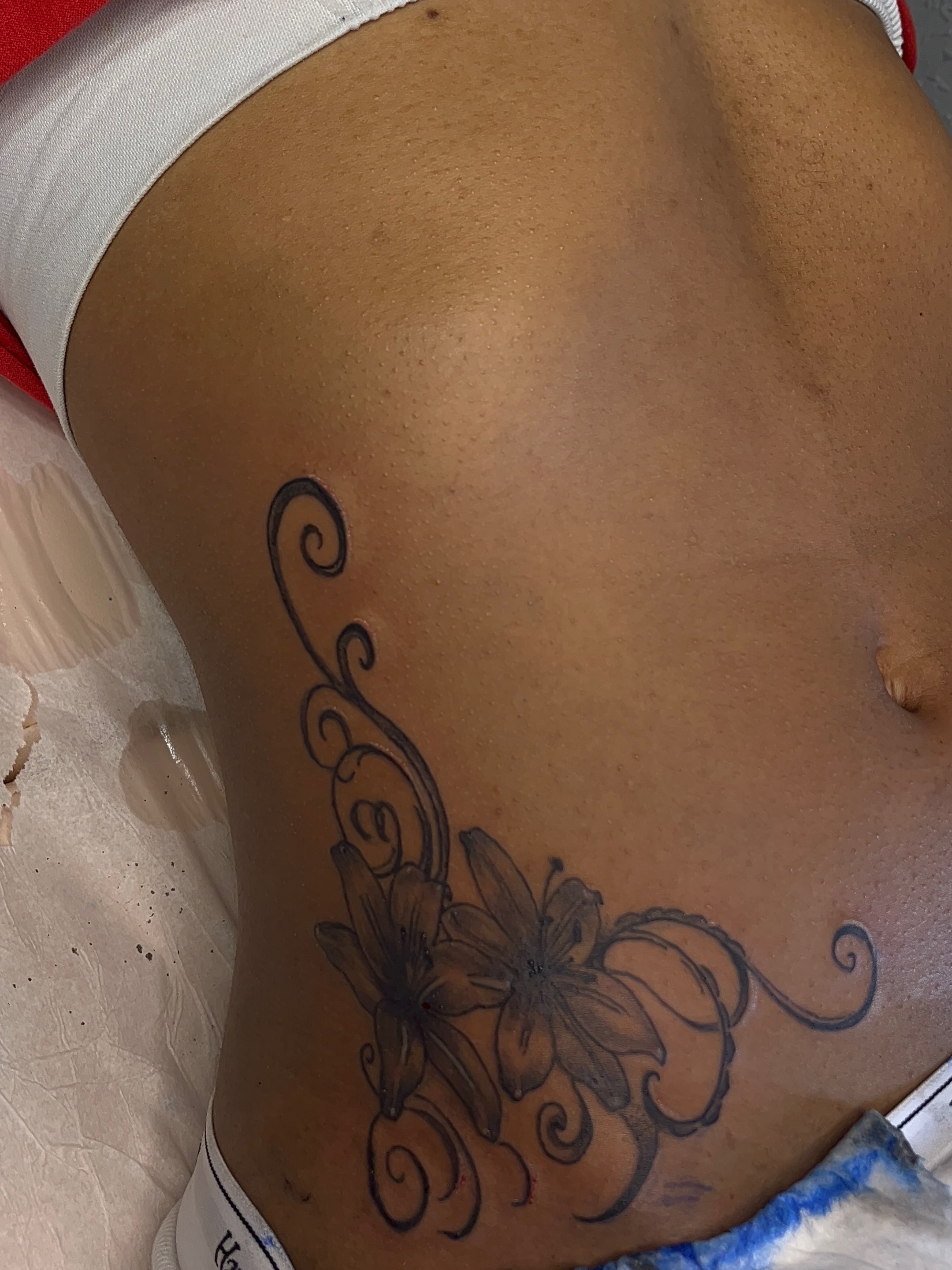 Lilies and swirls black and grey tattoo on the ribs by The inspo