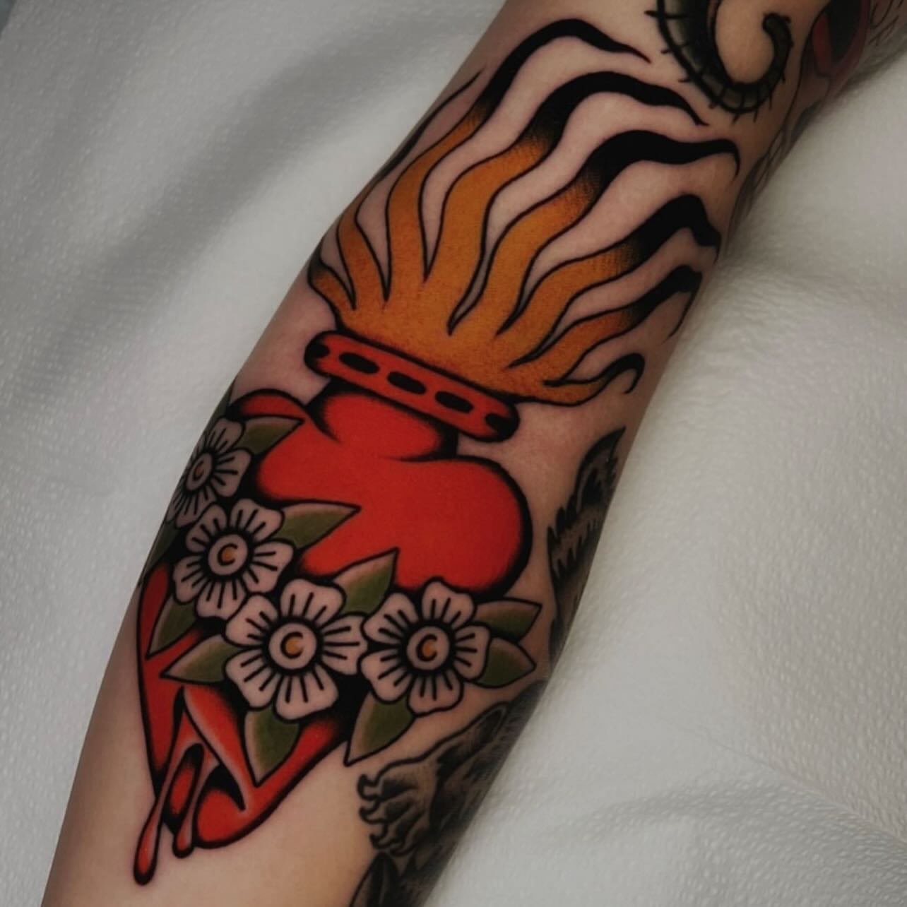 Heart with flames American traditional tattoo on the forearm by Hailey Johnson