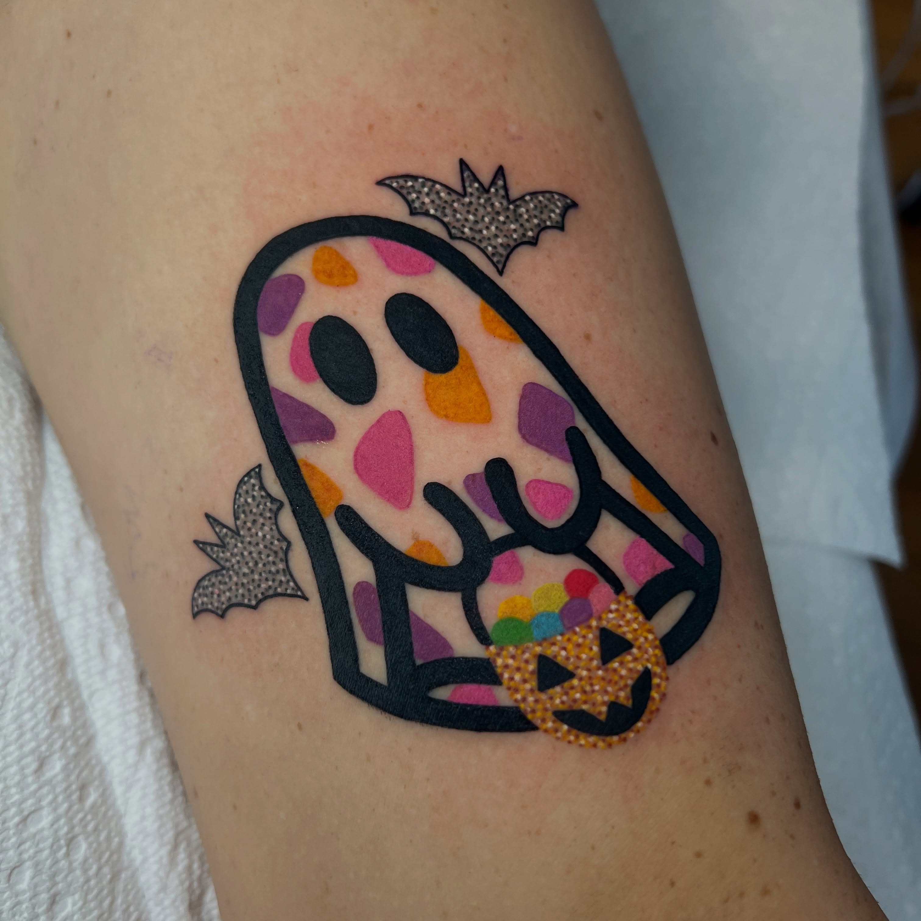 Ghost with candy trash polka tattoo on the forearm by Tattoo Artist
