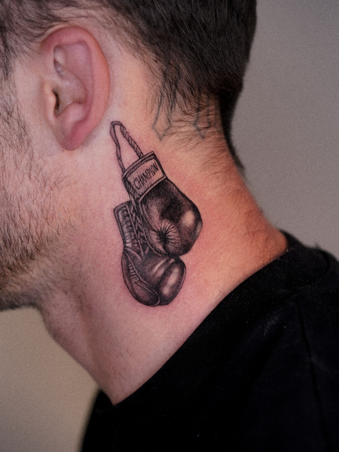 Boxing glove black and grey tattoo on the neck by Joy Christiana