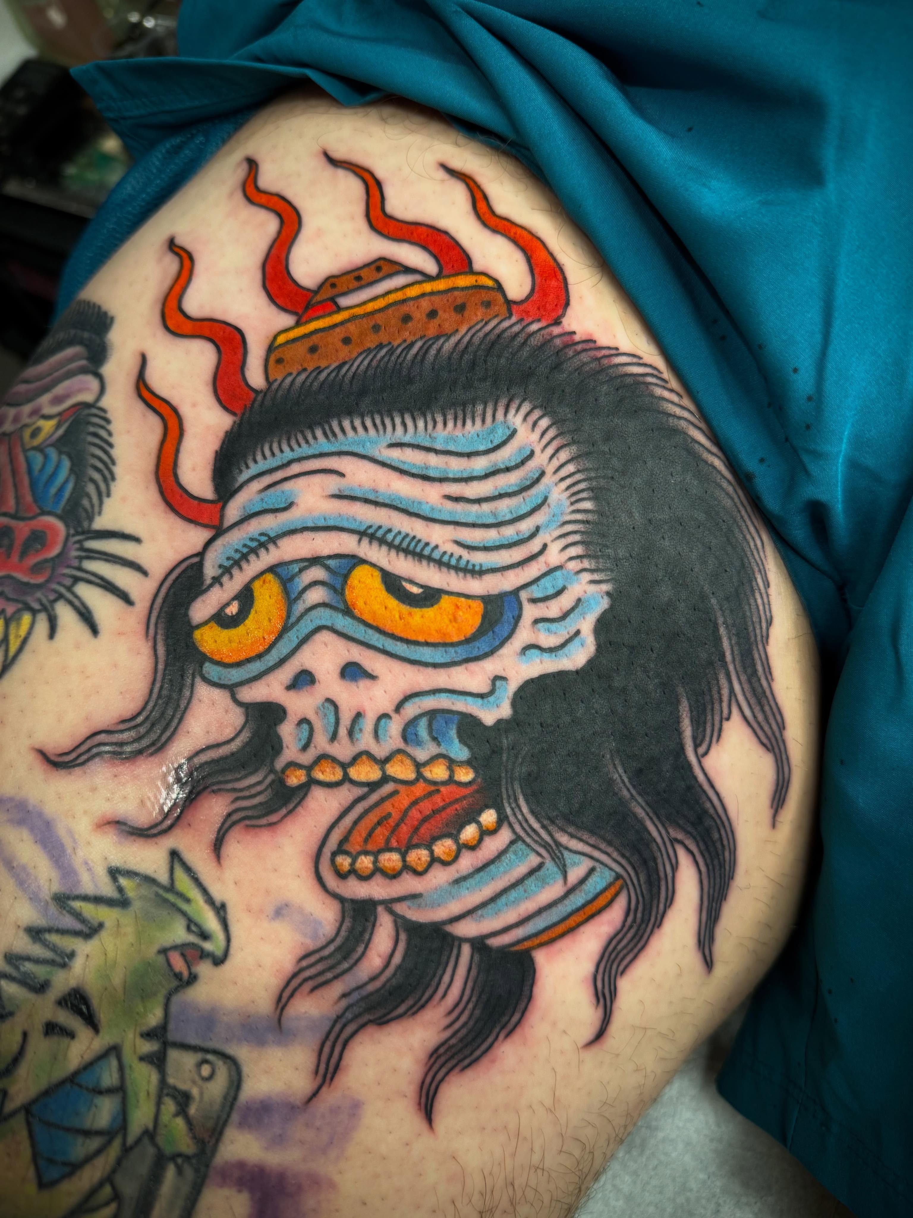 Japanese mask American traditional tattoo on the thigh by Noah Moretz