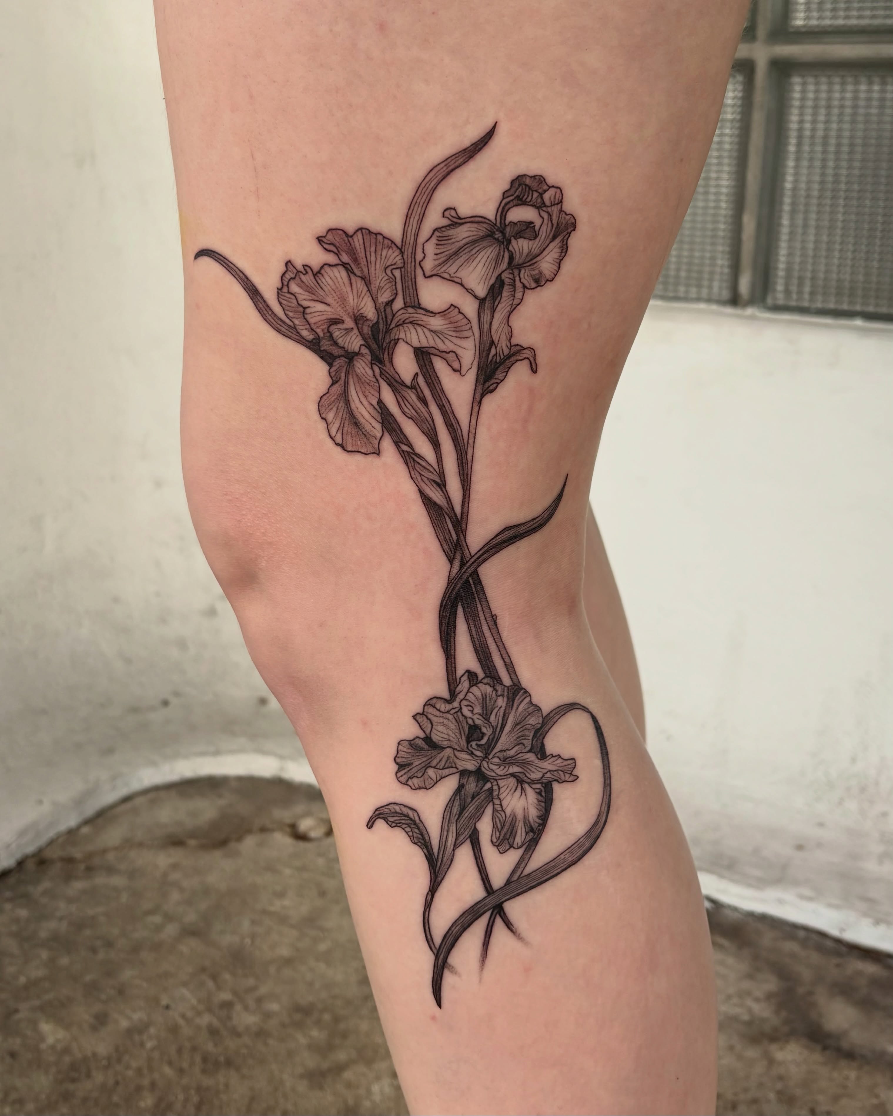 Iris black and grey tattoo on the thigh by Kylah Amin Tattoo