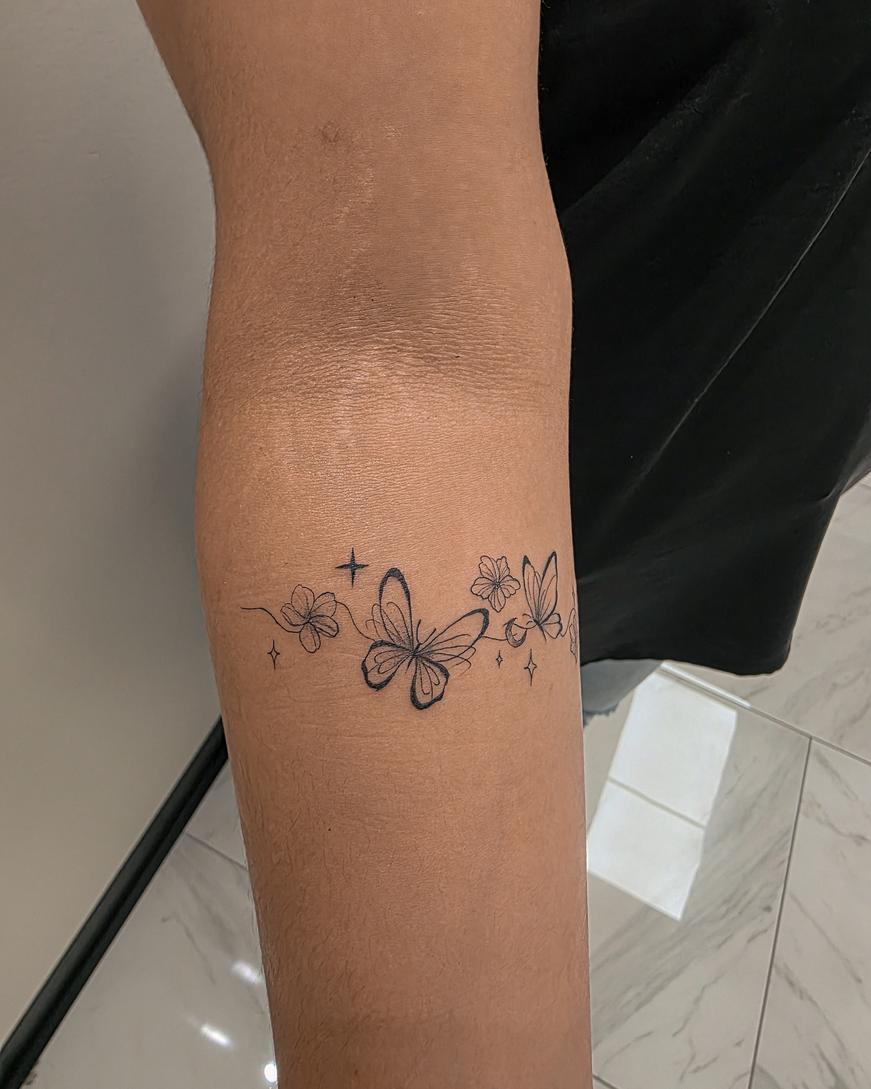 Butterfly and flowers black and grey tattoo on the forearm by Richmond tattoo shop, Richmond, Texas