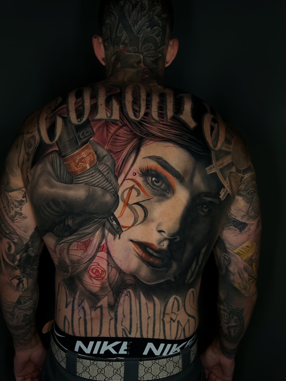 Woman with tattoo gun and lettering realism tattoo on the back by Dakota Case