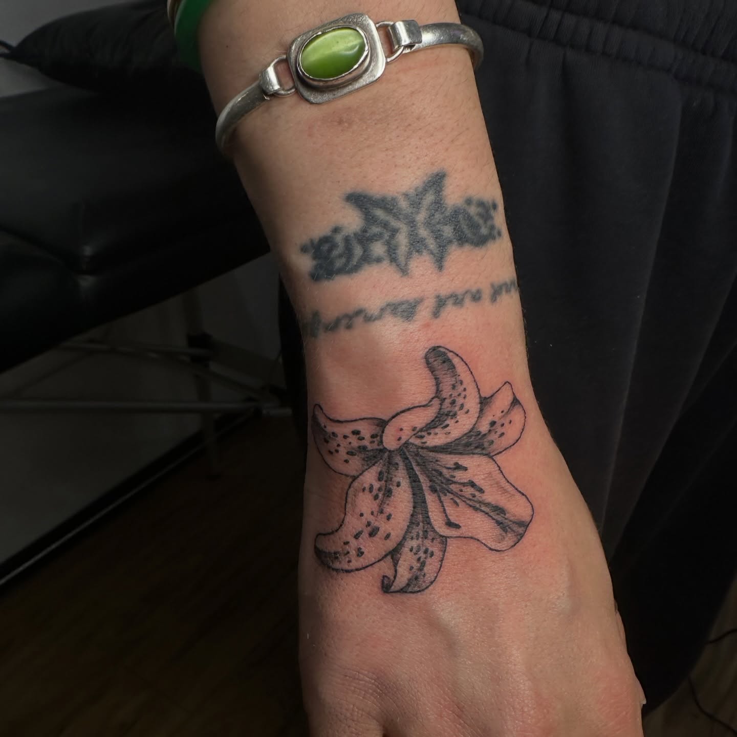Lily black and grey tattoo on the forearm by 𝓡𝓸𝓼𝓮 𝓗𝓪𝔂𝓮𝓼