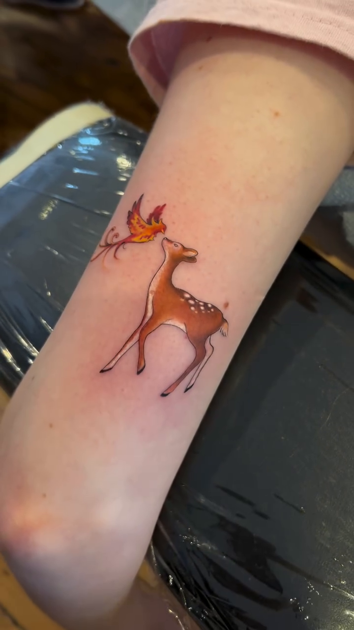 Deer with a bird fine line tattoo on the forearm by High Vibrations