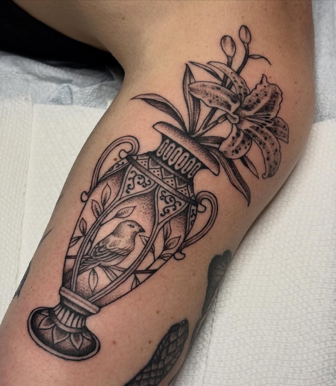 Bird in cage with lily realism tattoo on the forearm by Sydney Pflaumer