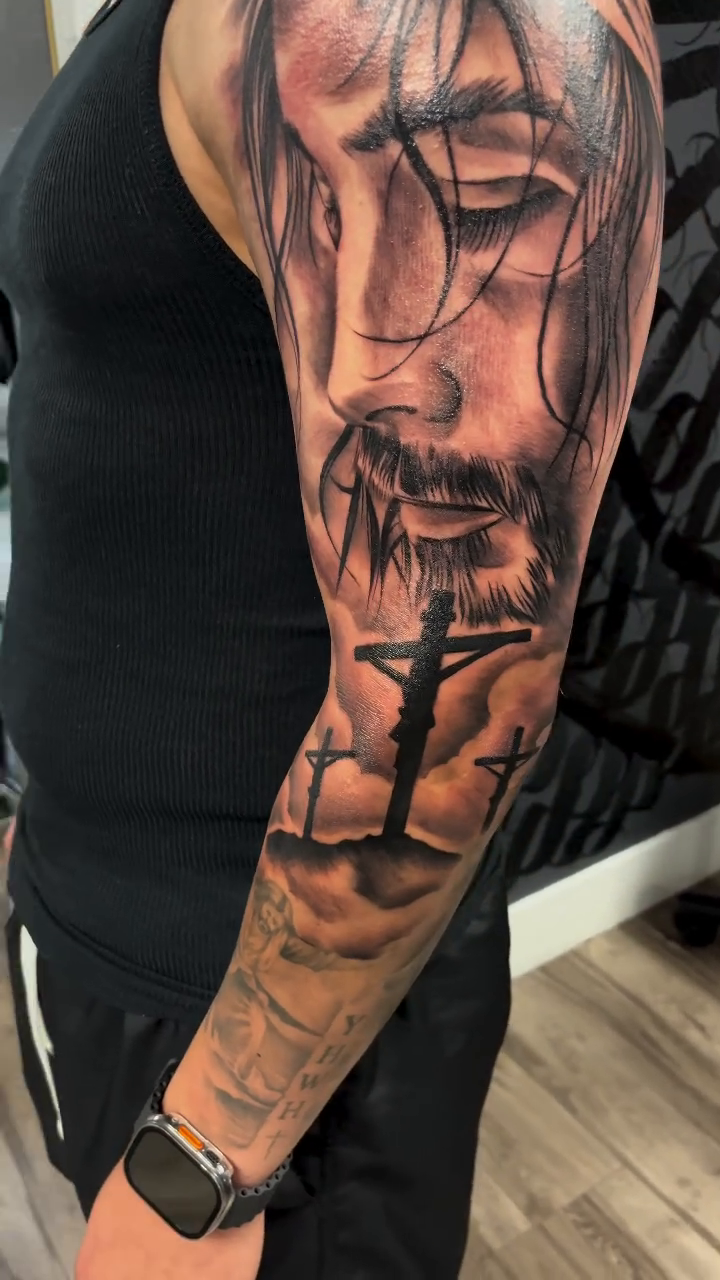 Jesus Christ sleeve Chicano tattoo on the upper arm by Brian Cruz Garcia