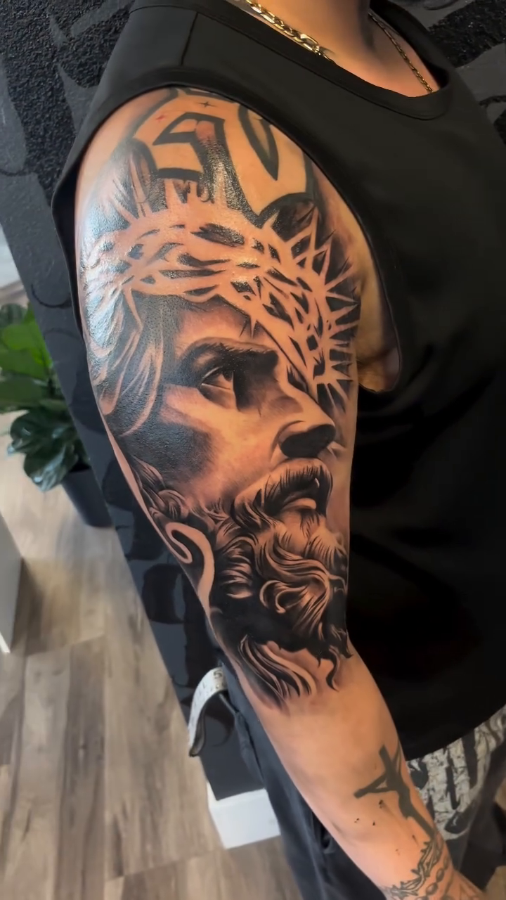 Jesus Christ portrait realism tattoo on the upper arm by Brian Cruz Garcia