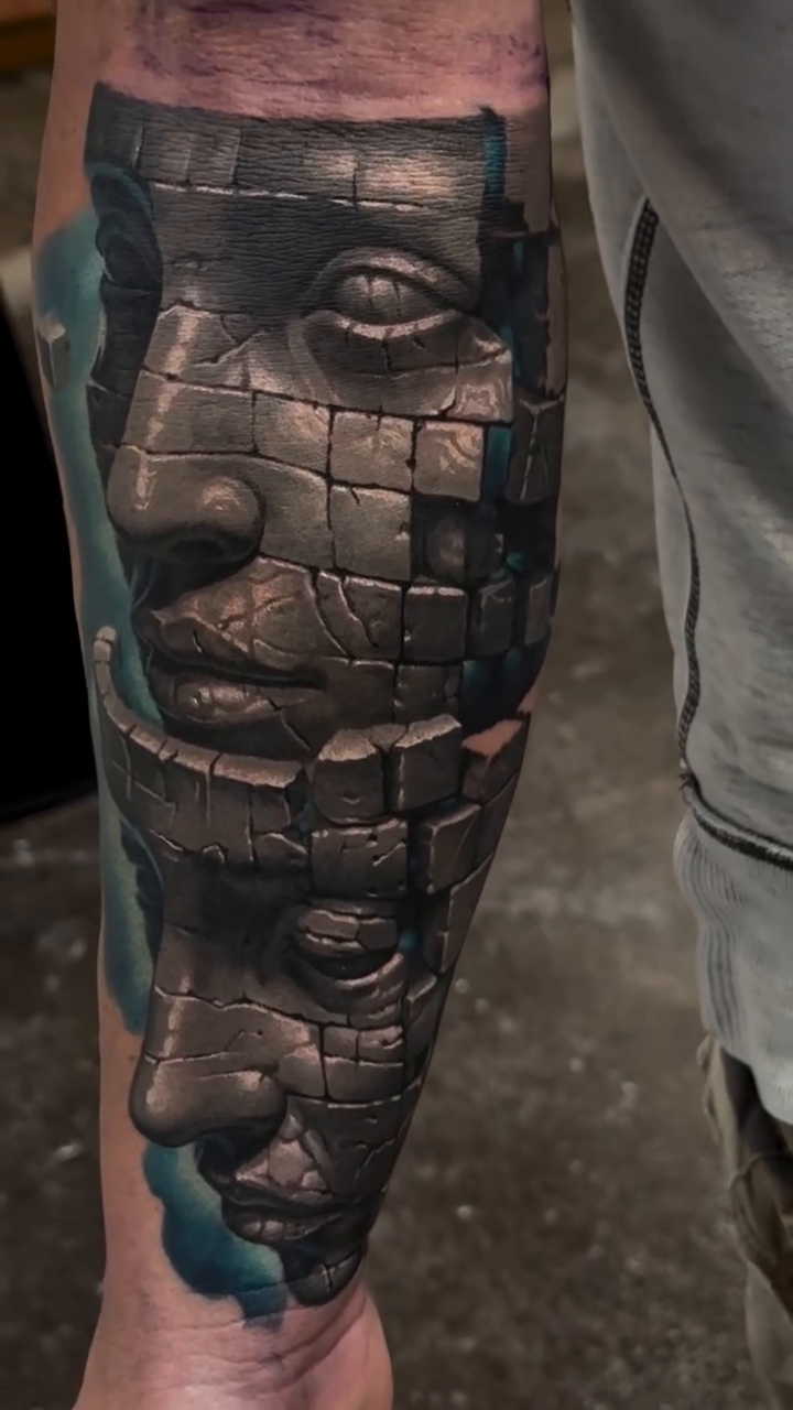 Fragmented stone faces surrealism tattoo on the forearm by Jacob Sheffield, Grand Junction, Colorado